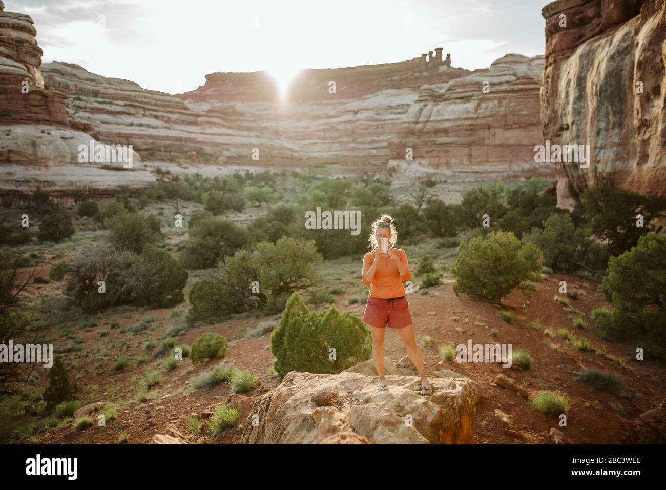 Frau in Trainingskleidung nimmt Foto mit Handy in Wüstenlicht Stockfoto