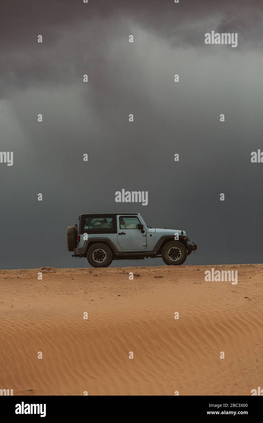 Jeep fährt über Sand Düne unbefestigten Straße auf der Straße Reise unter Sturmwolken Stockfoto