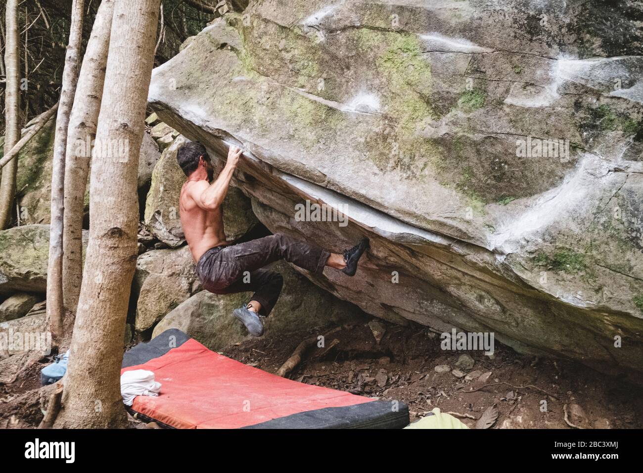 Ein männlicher Bergsteiger klettert draußen auf einen Felsen Stockfoto