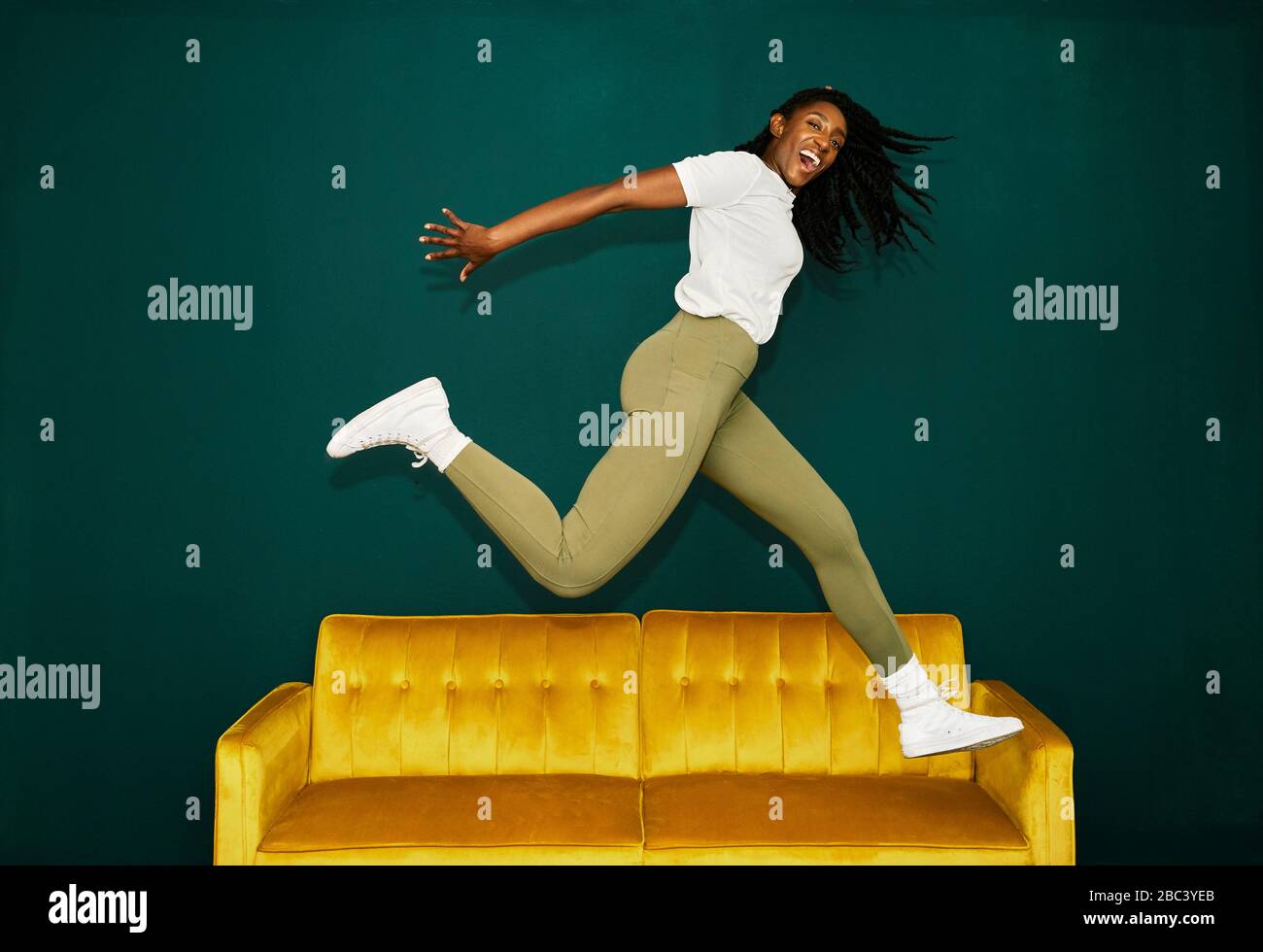 Junger schwarzer Student springt über einen gelben Trainer. Stockfoto