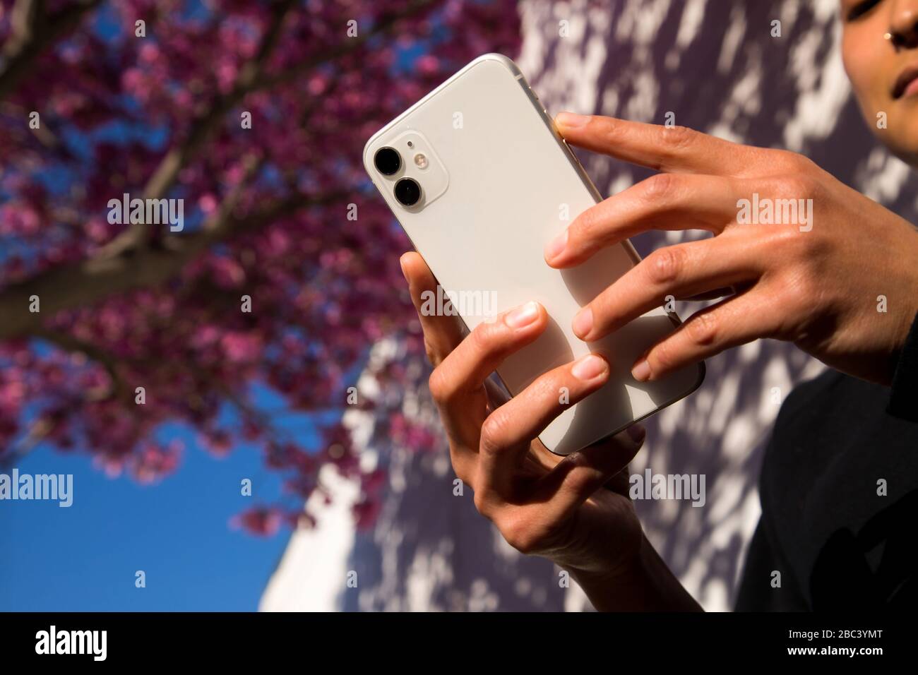Frau hält Handy im Frühling draußen Stockfoto