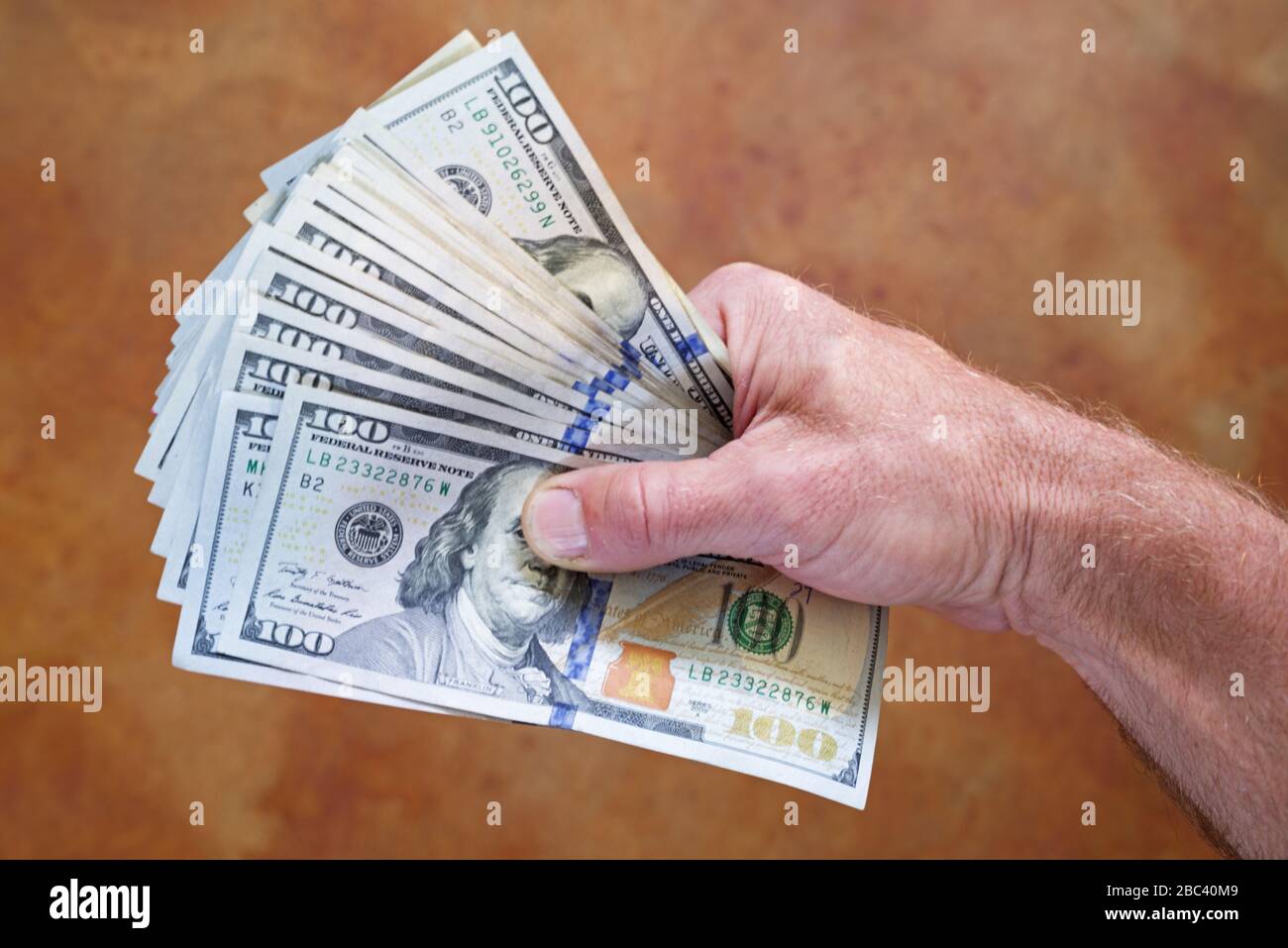 mans-hand-Holding fächelte Hunderte Dollar US-Rechnungen aus Stockfoto