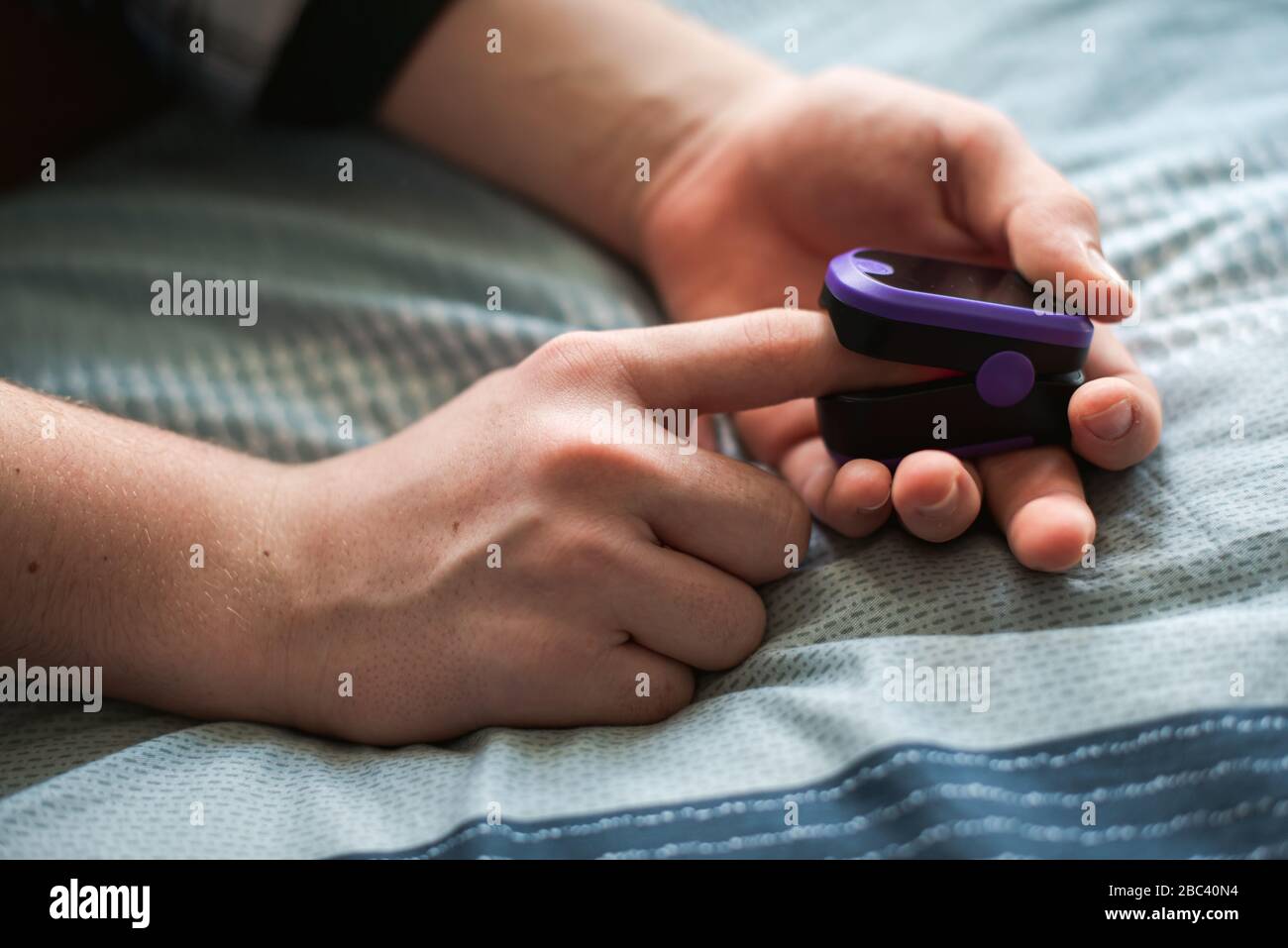 Nahaufnahme einer Person, die ein Pulsoximeter auf ihren Finger legt. Stockfoto