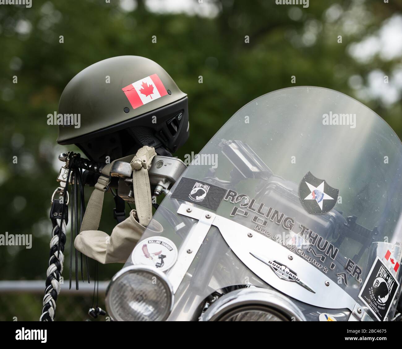 Grüner Kampfhelm mit kanadischem Symbol, der bei einer Veteranenveranstaltung am Lenker eines Motorrads hängt. Stockfoto