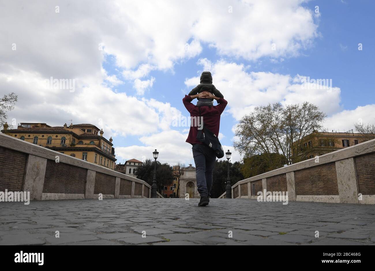 Rom, Italien. April 2020. Am 2. April 2020 spaziert ein Mann mit seinem Kind in Rom, Italien. Die Pandemie COVID-19 hat bis Donnerstag knapp 14.000 Menschenleben im eingesperrten Italien gefordert, was die Gesamtzahl der Infektionen, Todesfälle und Erholungen auf 115.242 nach den neuesten Daten des Zivilschutzministeriums des Landes brachte. Credit: Elisa Lingria/Xinhua/Alamy Live News Stockfoto