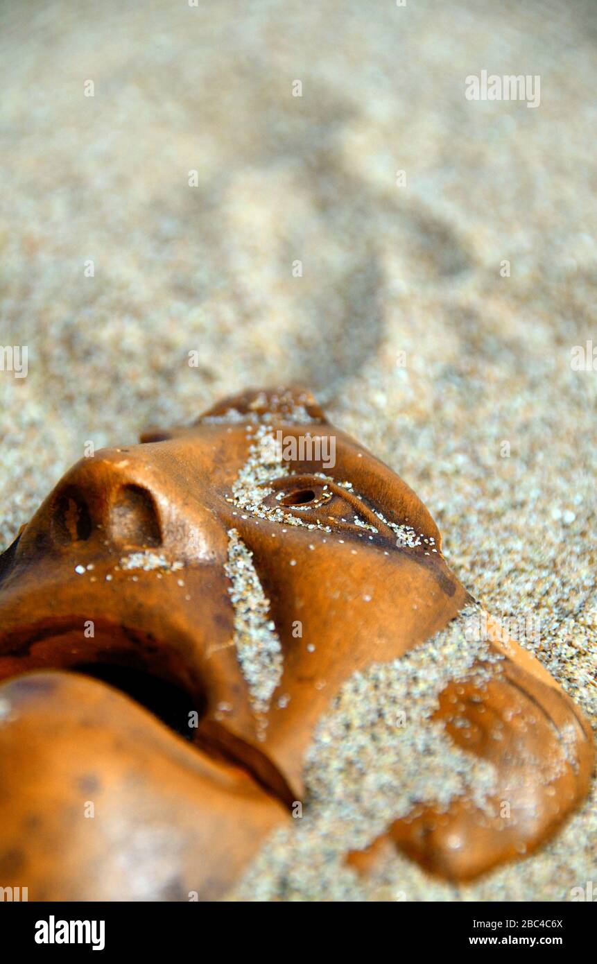 Zerbrochene tragische griechische Tonmaske im Sand Stockfoto