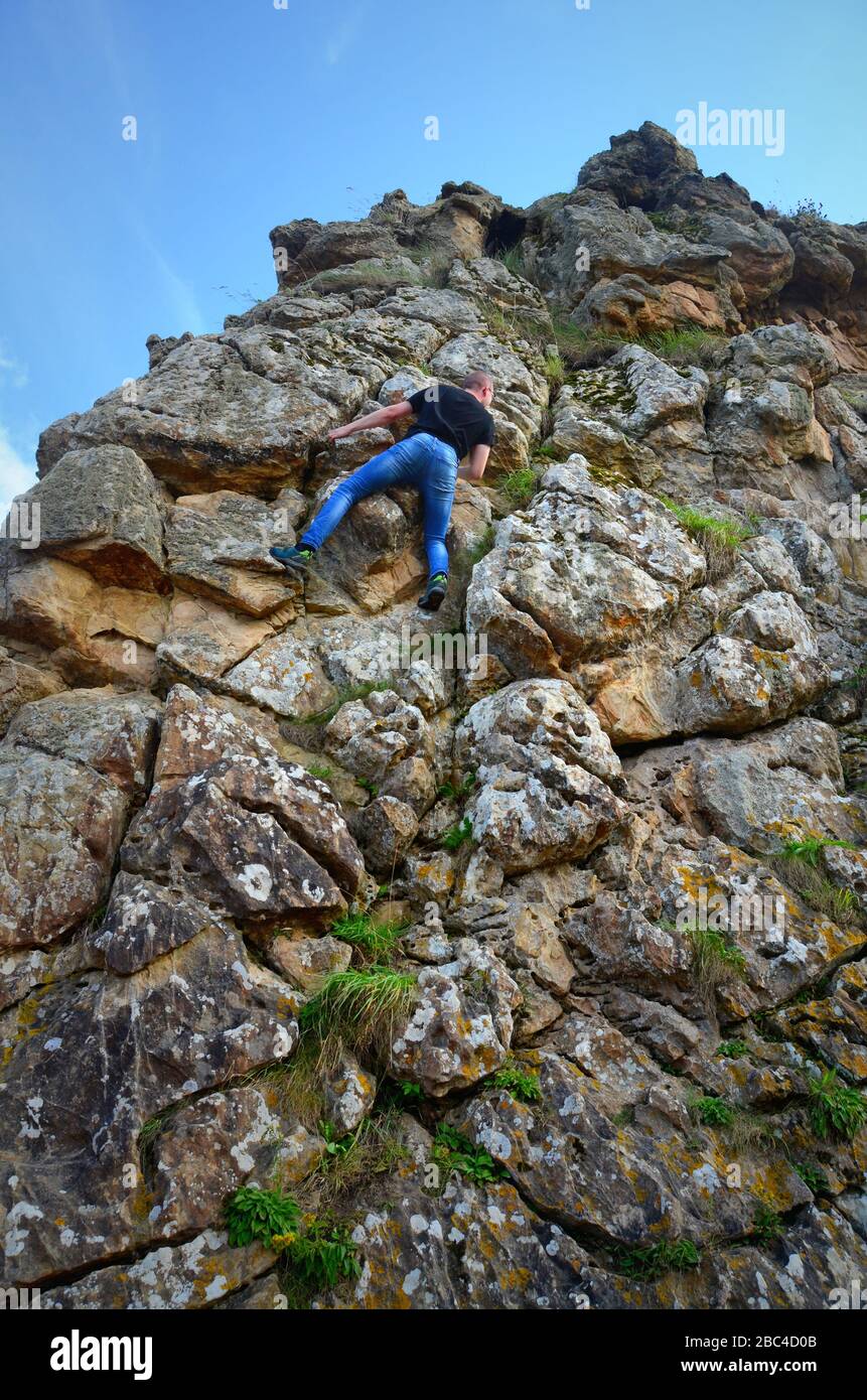Ein junger Mann/Teenager befreit sich von einem Felsvorsprung Stockfoto