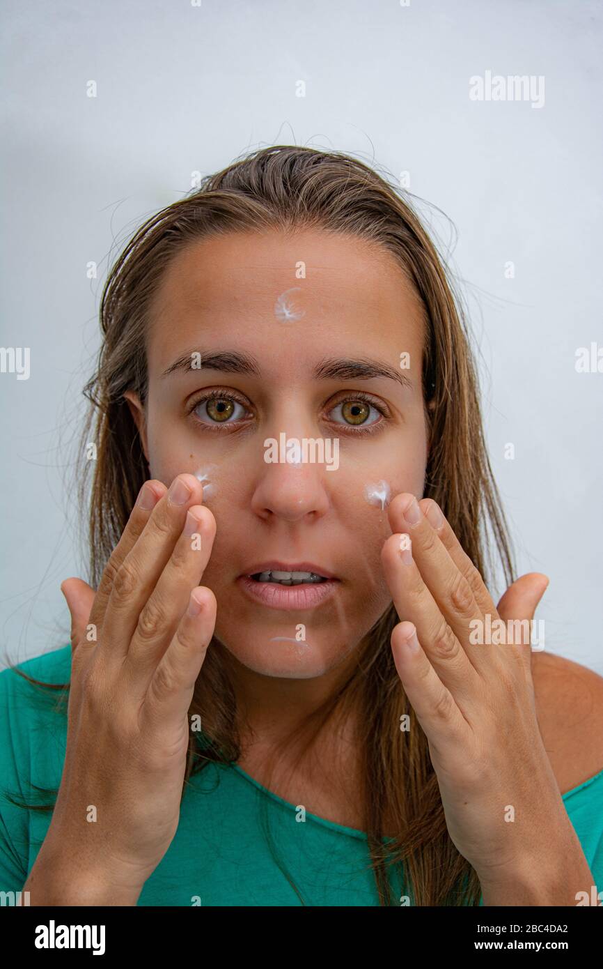 Frau, die Creme auf ihr Gesicht legt, um es zu hydratisieren Stockfoto