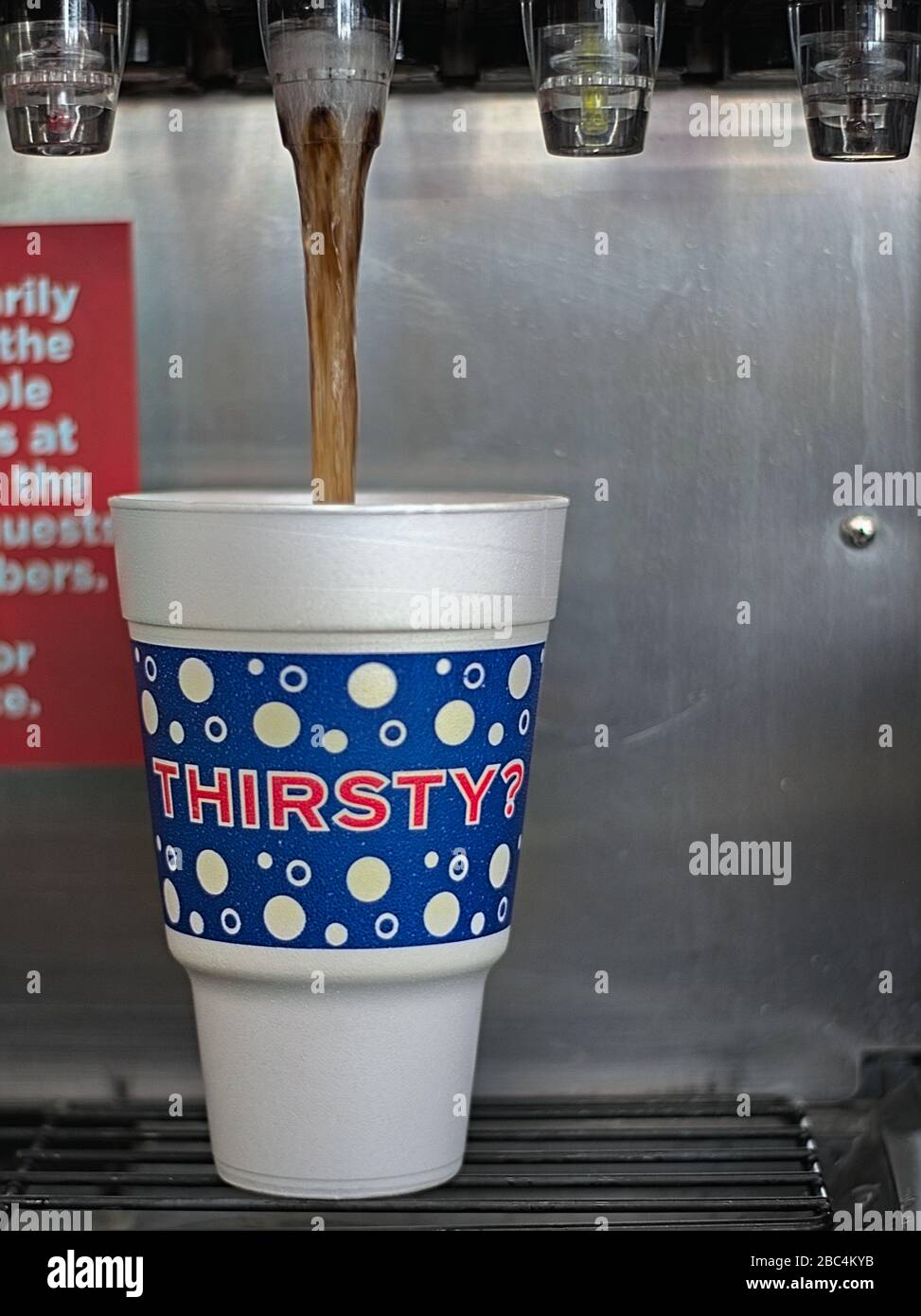 32-Unze Styrofoam Fountain Tasse mit dunkelbraunem Carbonatsodagetränk aus der Maschine in der Tankstelle des Convenience Store gefüllt. Stockfoto