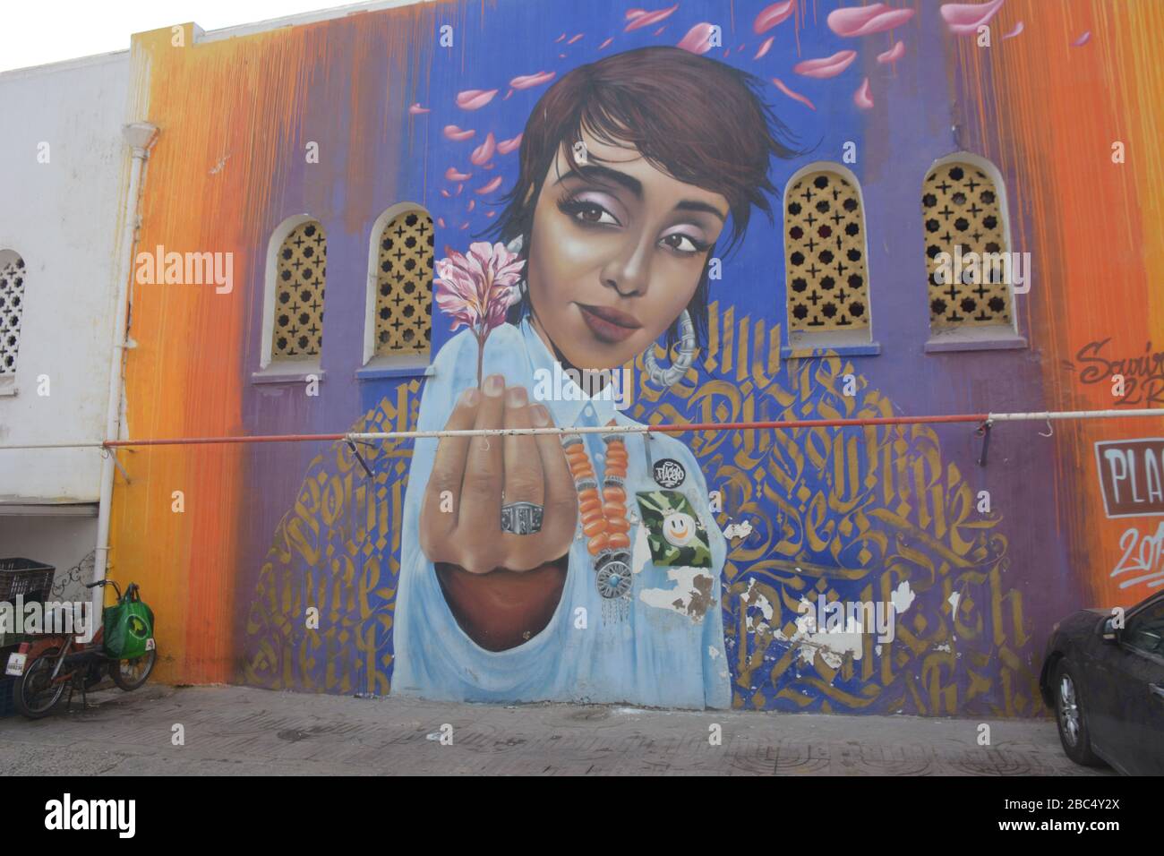 Ein großes Wandbild einer Frau mit kurzen Haaren und einer rosa Blume bedeckt eine Wand in markanten Street Art im Zentrum von Casablanca, Marokko. Stockfoto