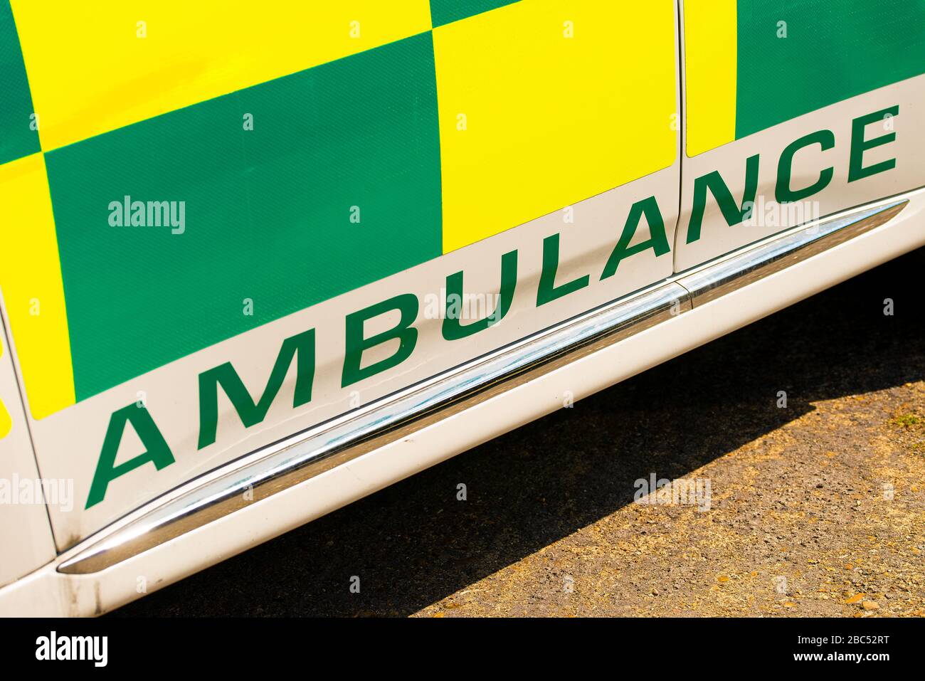 Hochwinkeliger Blick auf das SCHILD FÜR RETTUNGSWAGEN bei gut sichtbarer, grün-gelber NHS-Notarzteinsatzfahrzeug. Stockfoto