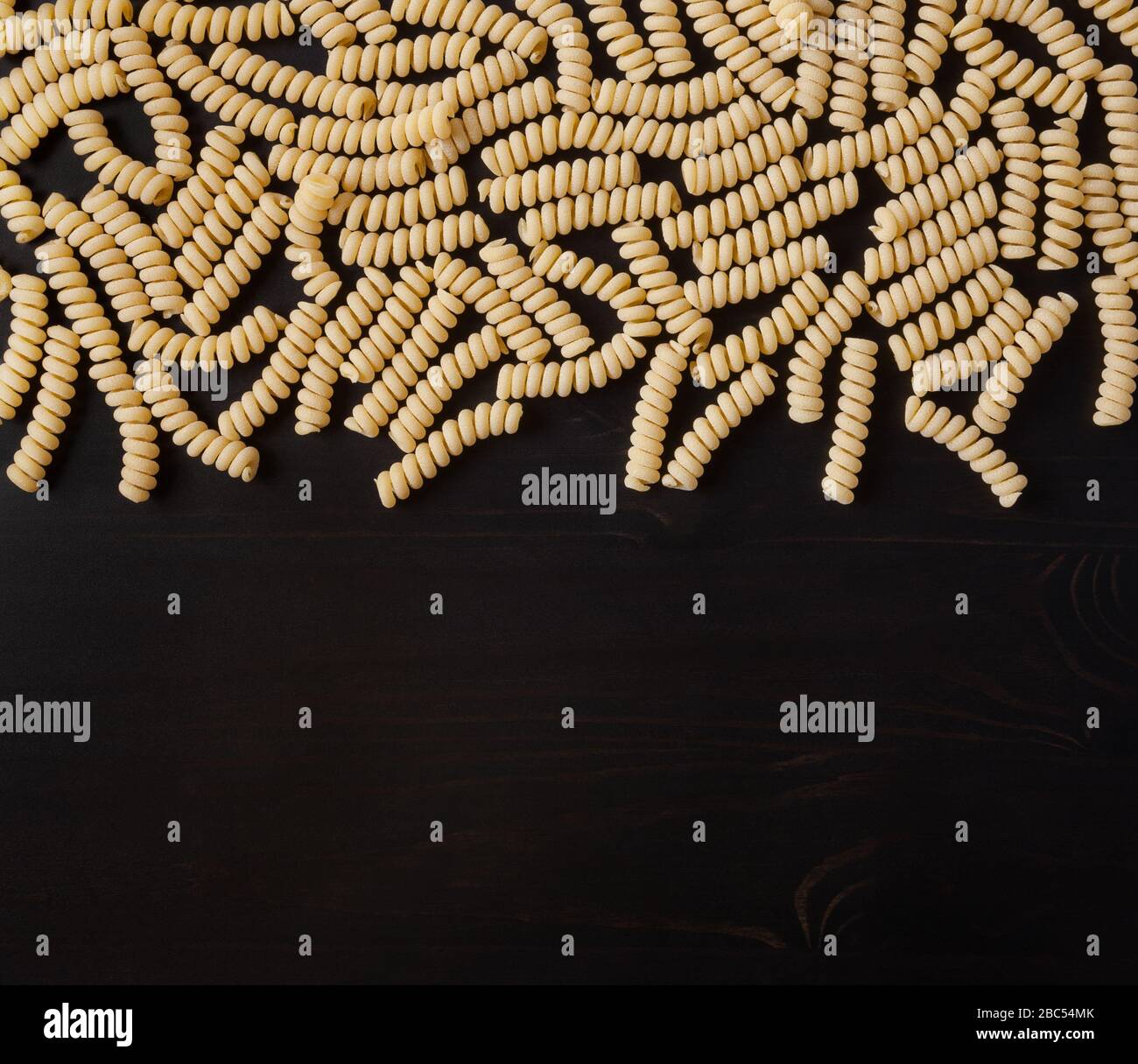 Uncooked Fusilli corti bucati Pasta auf schwarzem Hintergrund Stockfoto