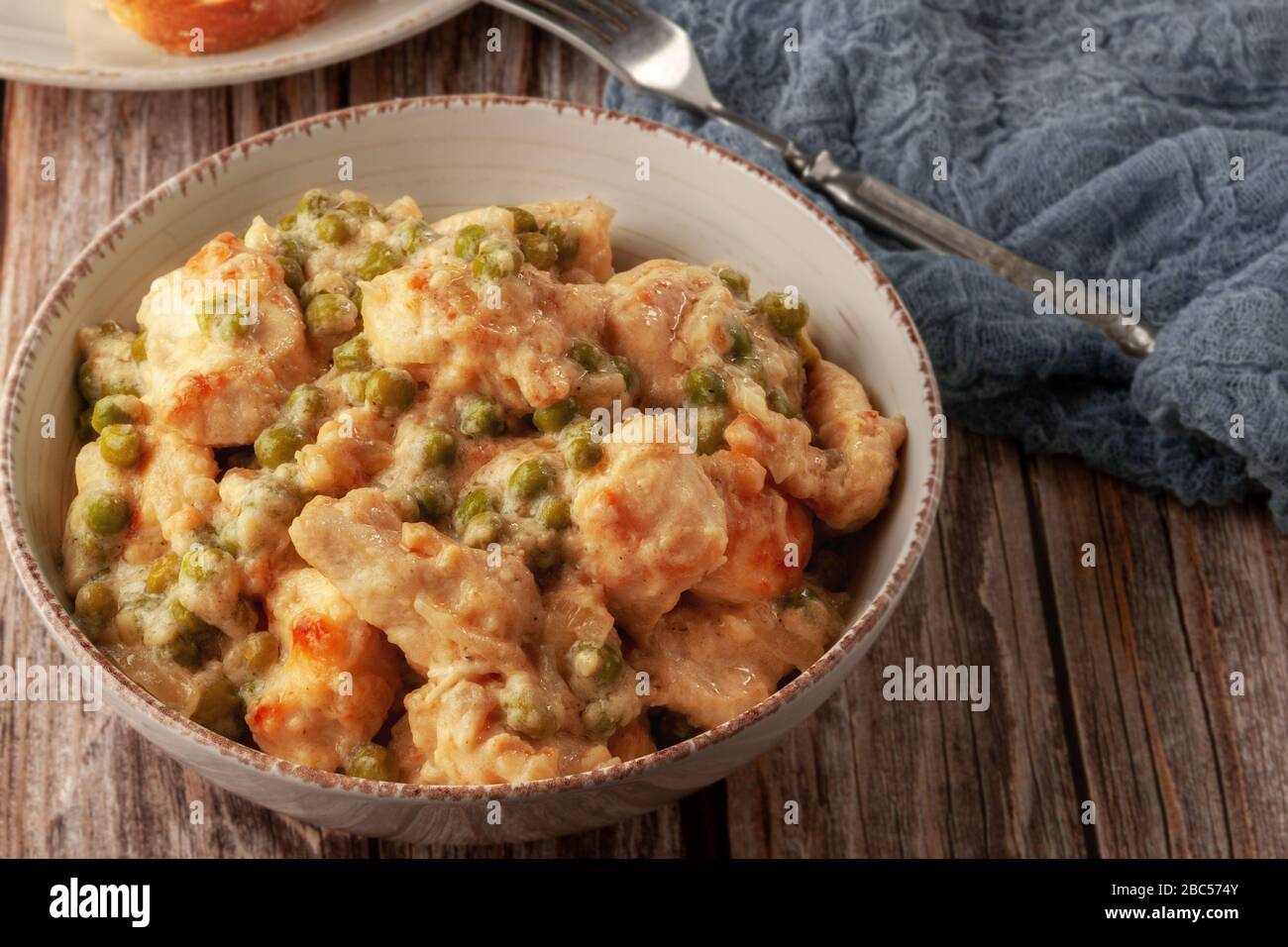 Geschmortes Hühnerfilet mit grünen Erbsen auf einem Holztisch Stockfoto