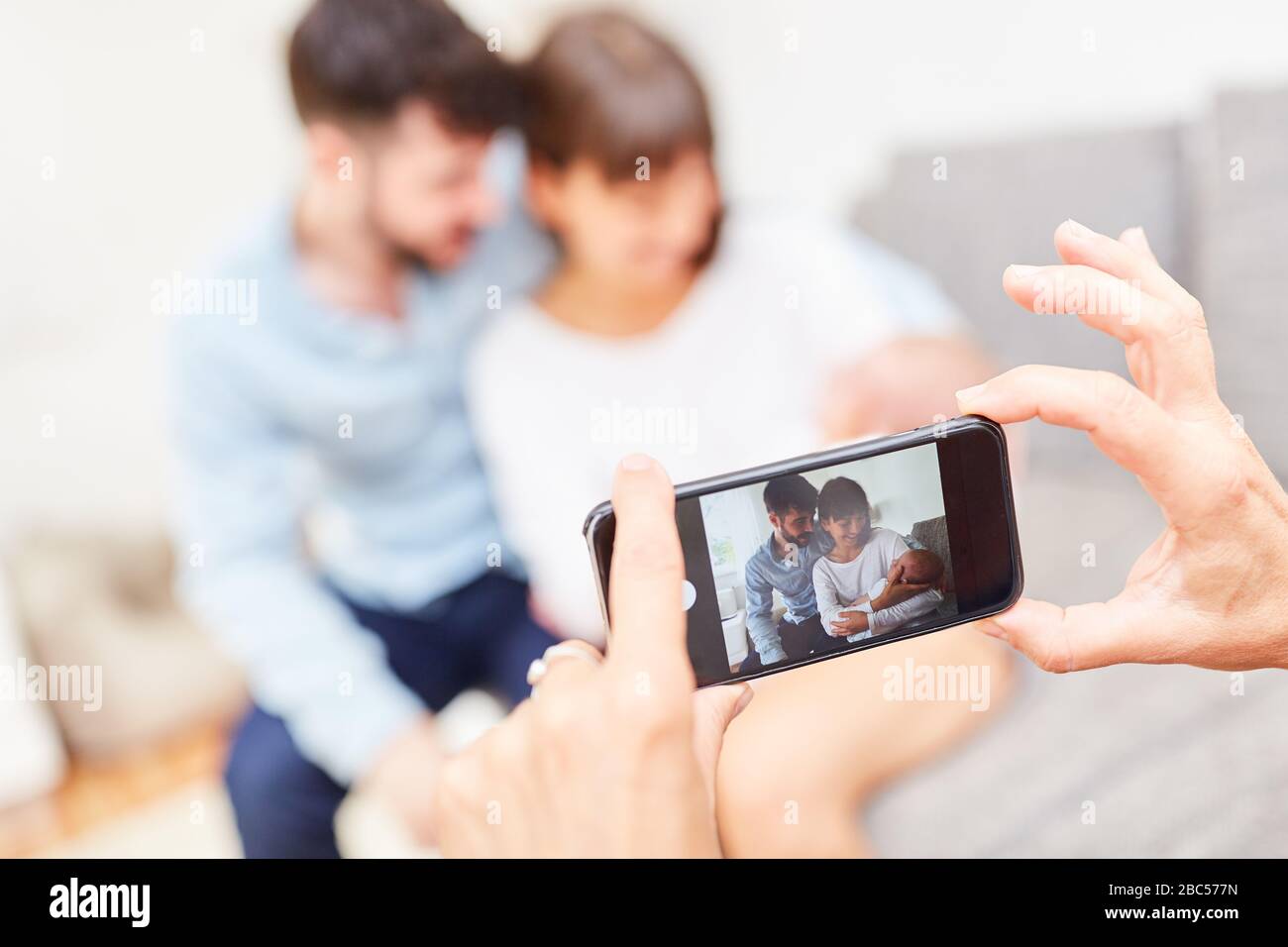 Smartphone macht sich mit einem neugeborenen Baby ein Bild von glücklichen Eltern Stockfoto