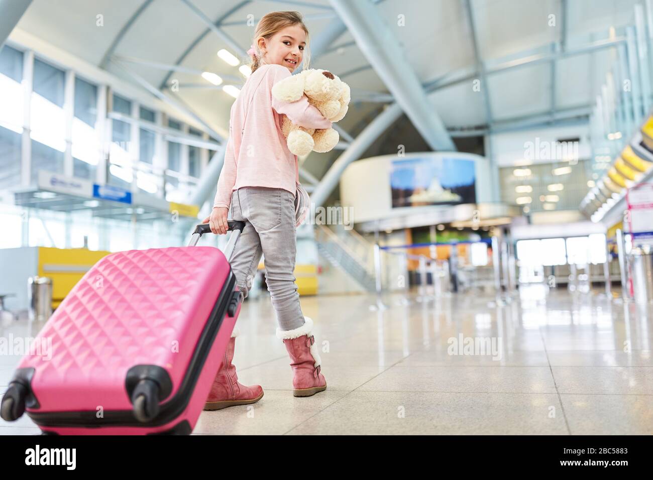 Allein fahrende Kinder mit Koffer und kuscheligen Spielzeug im Flughafenterminal oder Bahnhof Stockfoto
