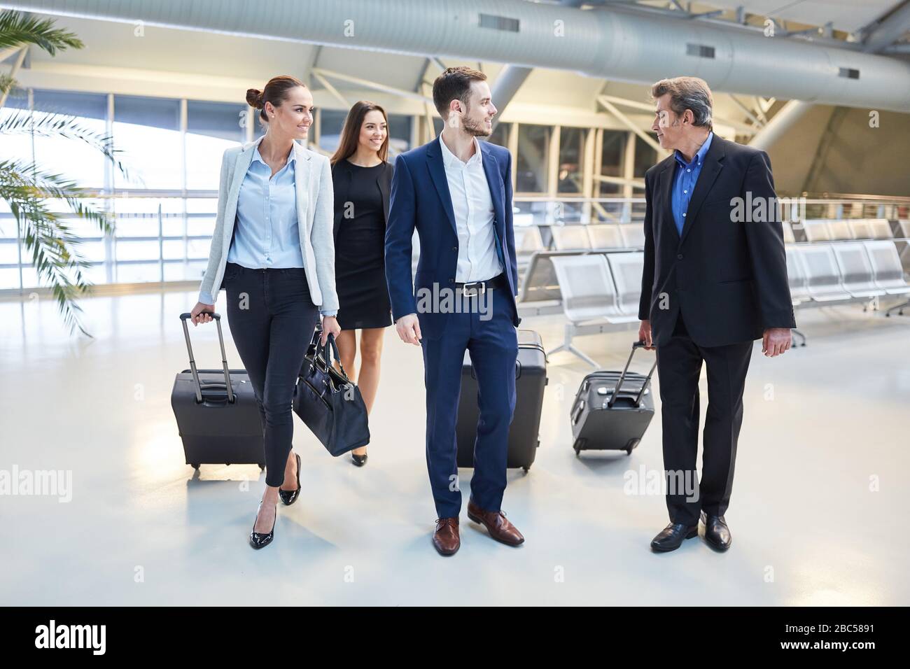 Erfolgreiche Geschäftsleute reisen als Team mit Gepäck im Flughafen zusammen Stockfoto
