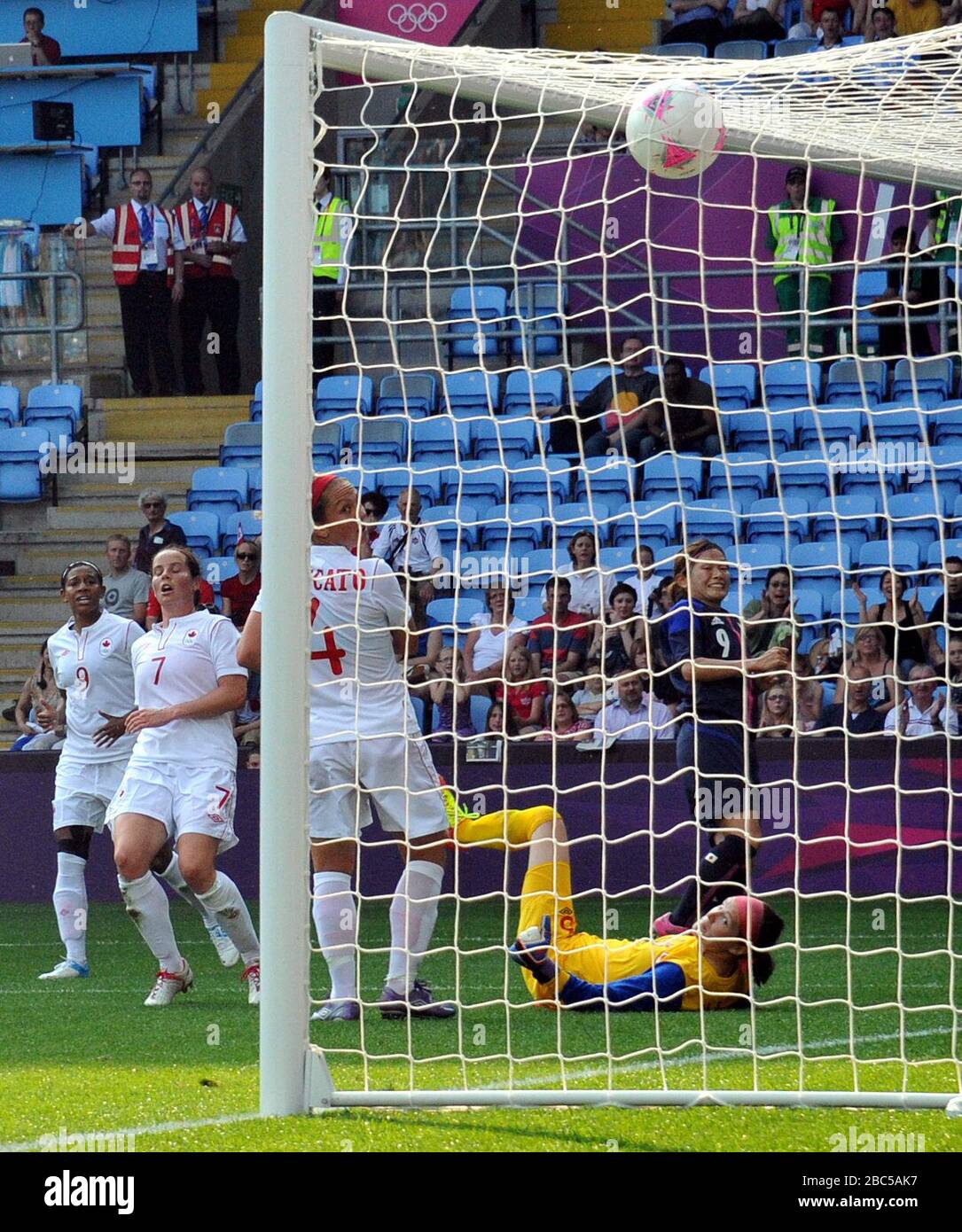 Die japanische Nahomi Kawasumi (9) erzielt ihr Eröffnungsziel hinter Kanadas Torhüter Erin McLeod während des Spiels der Damen Football, First Round, Gruppe F im City of Coventry Stadium, Coventry. Stockfoto