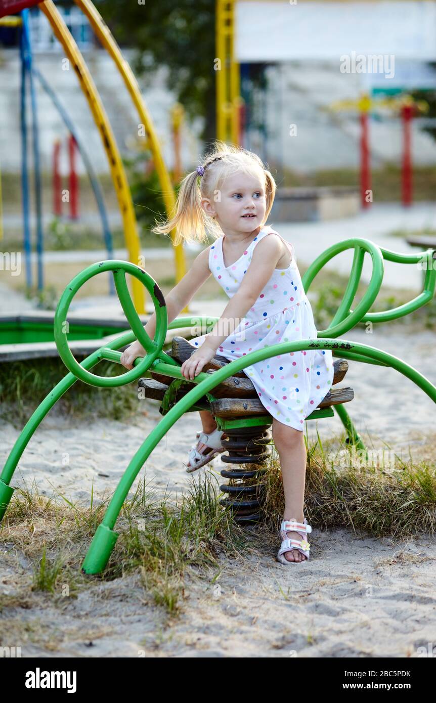 Fröhliches lächelndes Mädchen, das auf dem Spielplatz im Park spielt. Mädchen, die Spaß haben Stockfoto