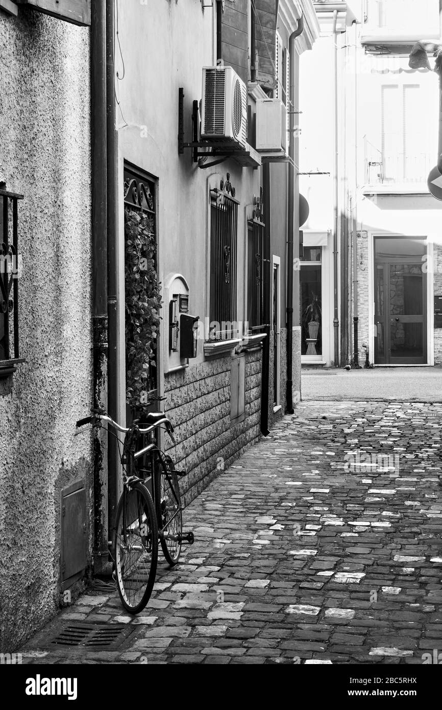 Straße und Fahrrad in der Nähe der Mauer in Rimini, Italien. Italienisches Schwarz-Weiß-Stadtbild Stockfoto