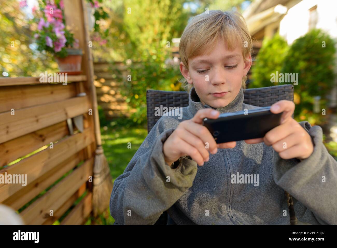 Junger gutaussehender Junge mit Telefon im Hinterhof Stockfoto