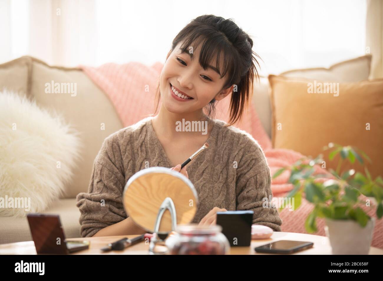 Junge chinesische Frau, die zu Hause Make-up anwendet Stockfoto