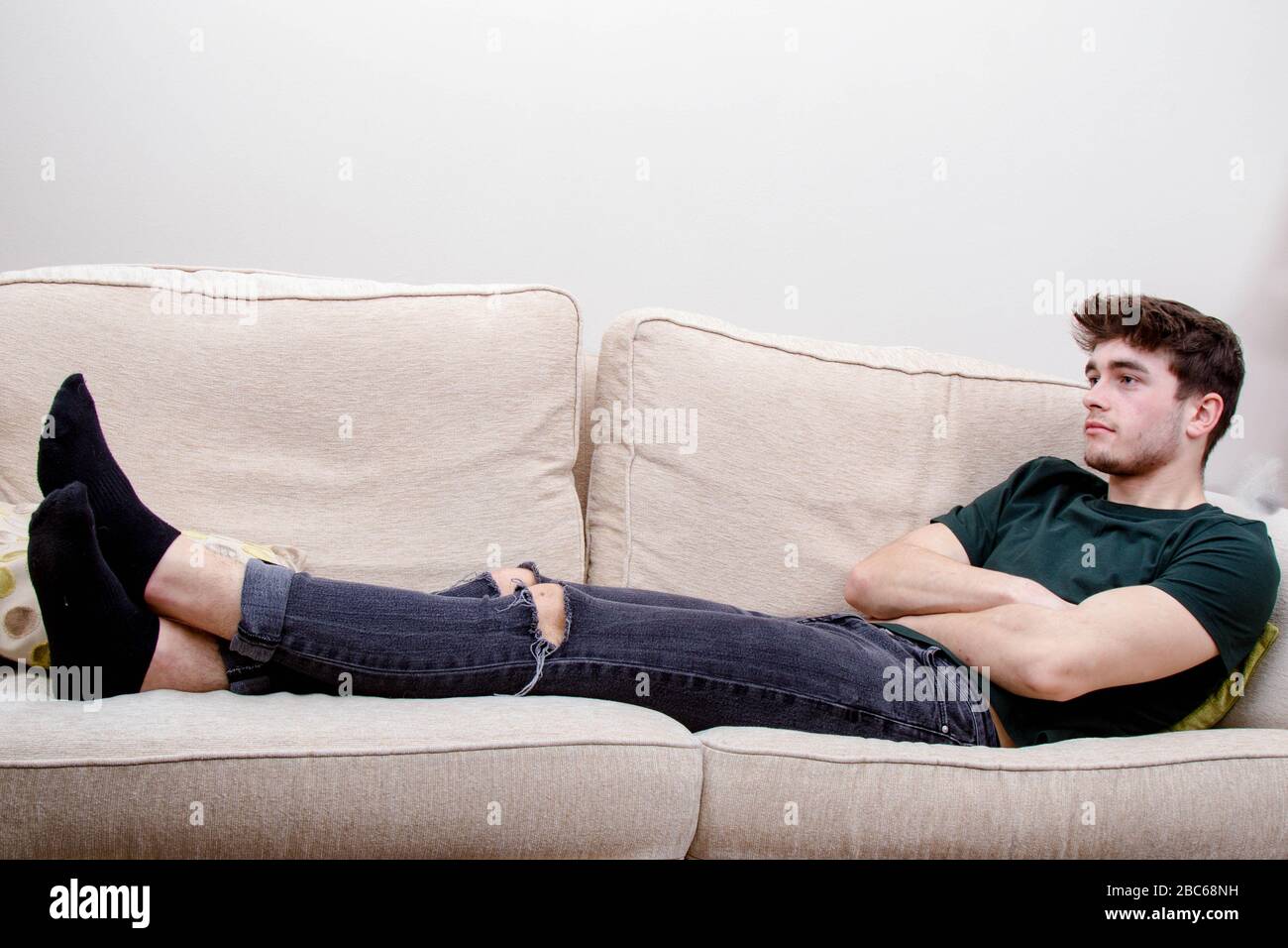 Ein junger Erwachsener, der auf einem Sofa liegt Stockfoto