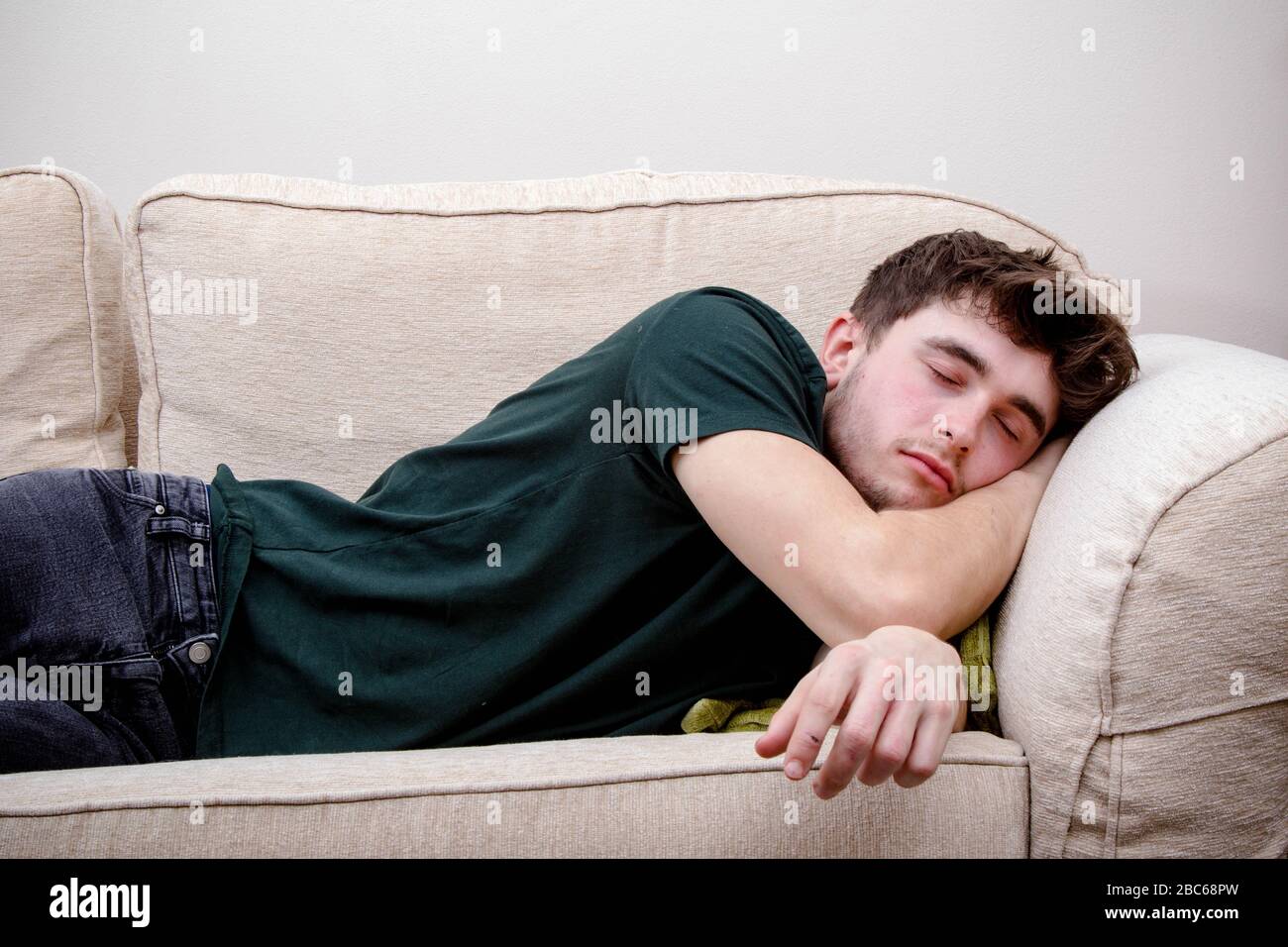 Ein junger Erwachsener schläft auf einem Sofa Stockfoto