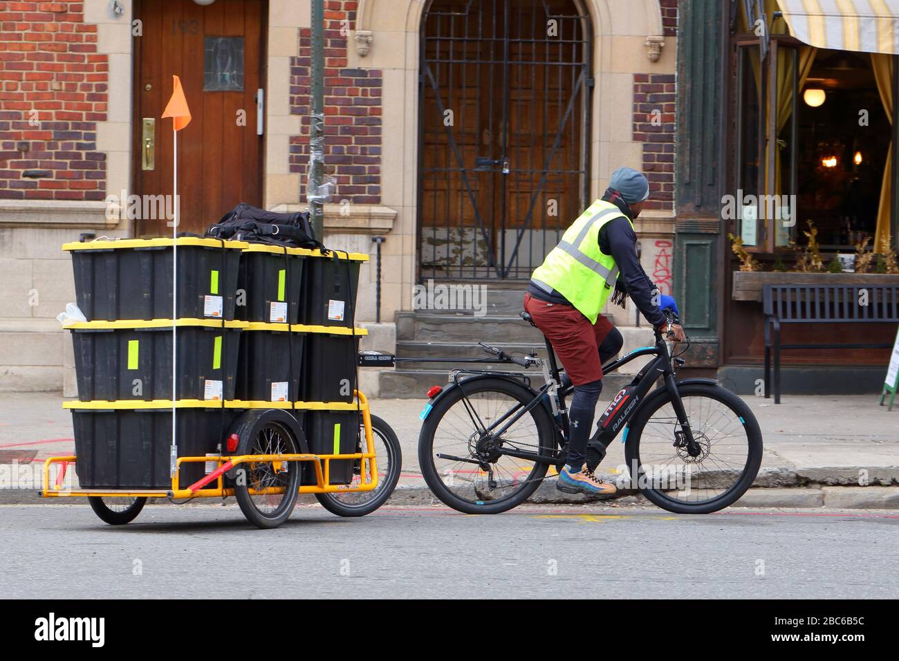 Ein Breakaway Fahrradkurier, der Lebensmittelgeschäfte mit einem Elektrobike und Carla Cargo Fahrradtrailer in New York, New York, New York, USA, liefert. Stockfoto