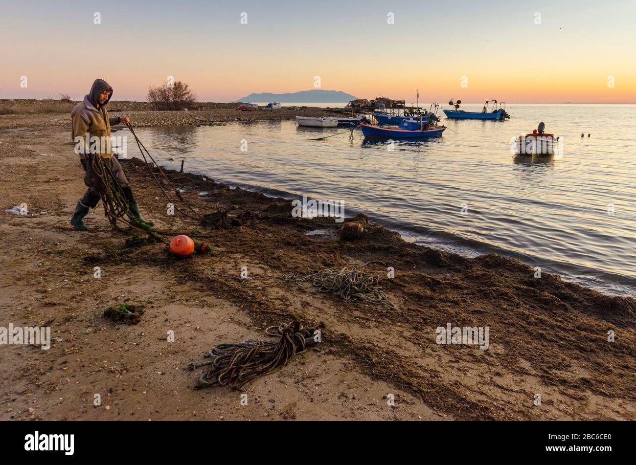 Ein Fischer räumt alte Seile und Detritis vom Strand in Alexandroupoli Evros Griechenland ab Stockfoto