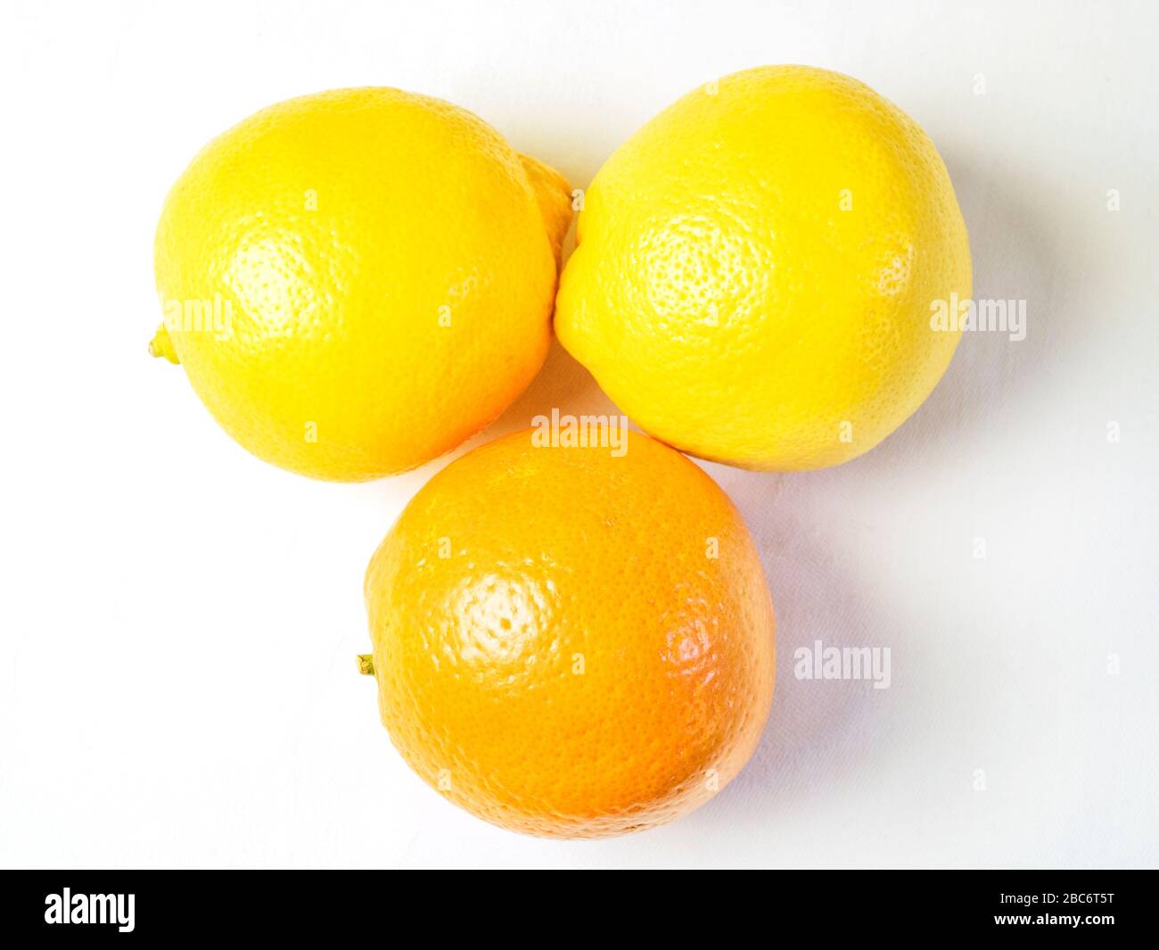 Ein Orange und zwei Zitronen von oben auf einem weißen Tischtuch Stockfoto