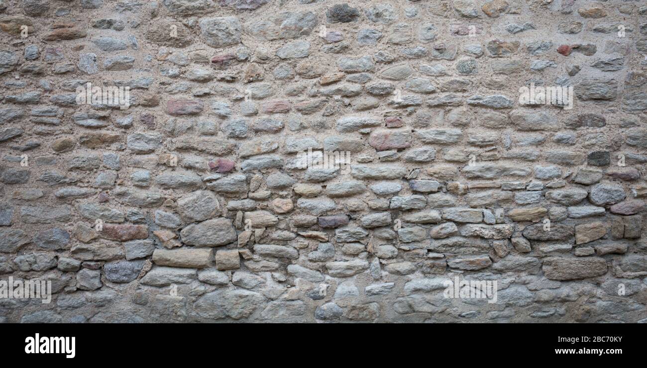 Alte steingraue Wand aus großen kleinen Natursteinen Stockfoto