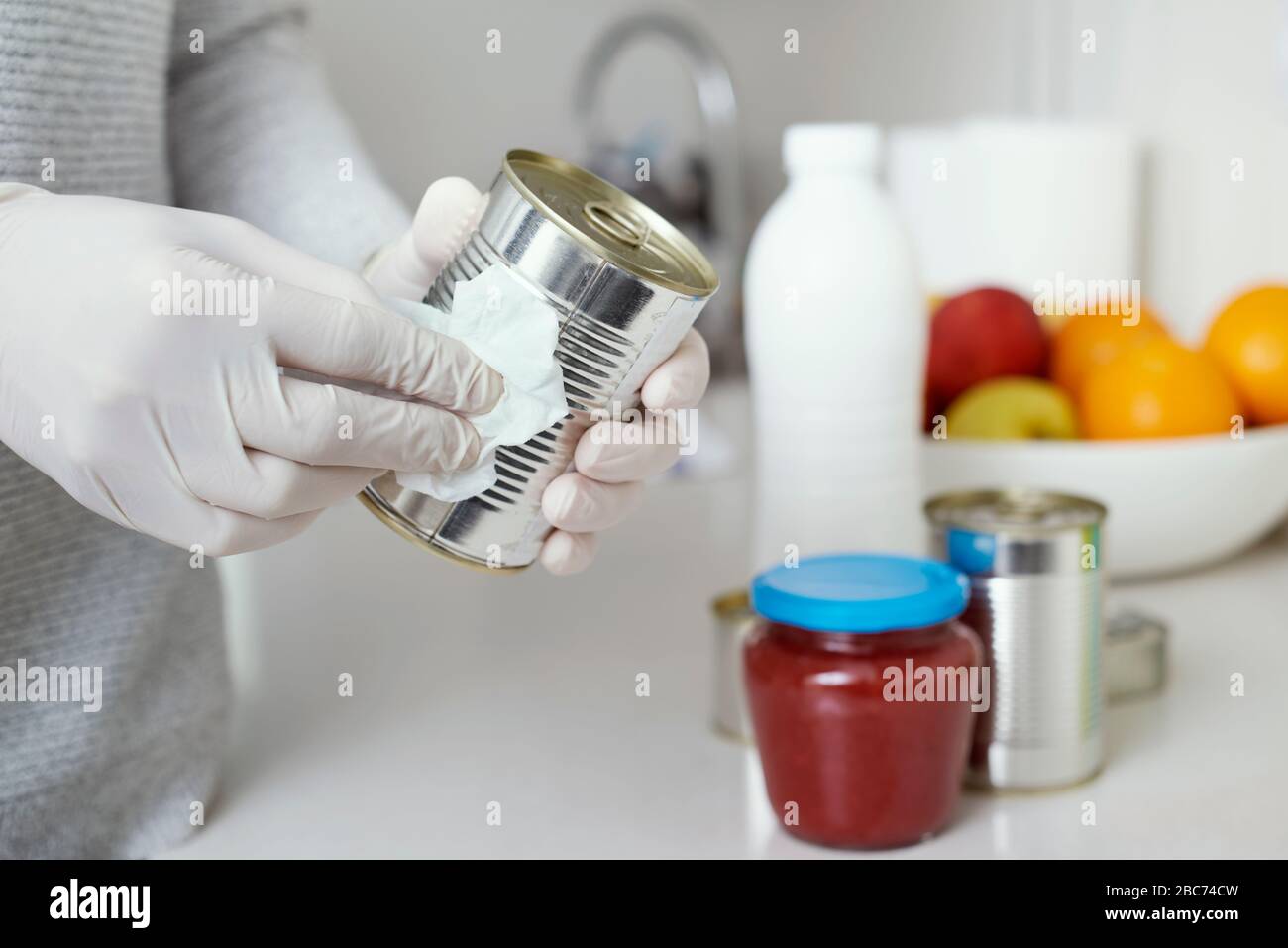 Nahaufnahme eines Mannes in der Küche, mit Latexhandschuhen, Reinigungsmitteldosen und Gläsern, frisch gekauft, mit einem Desinfektionsmittel Stockfoto