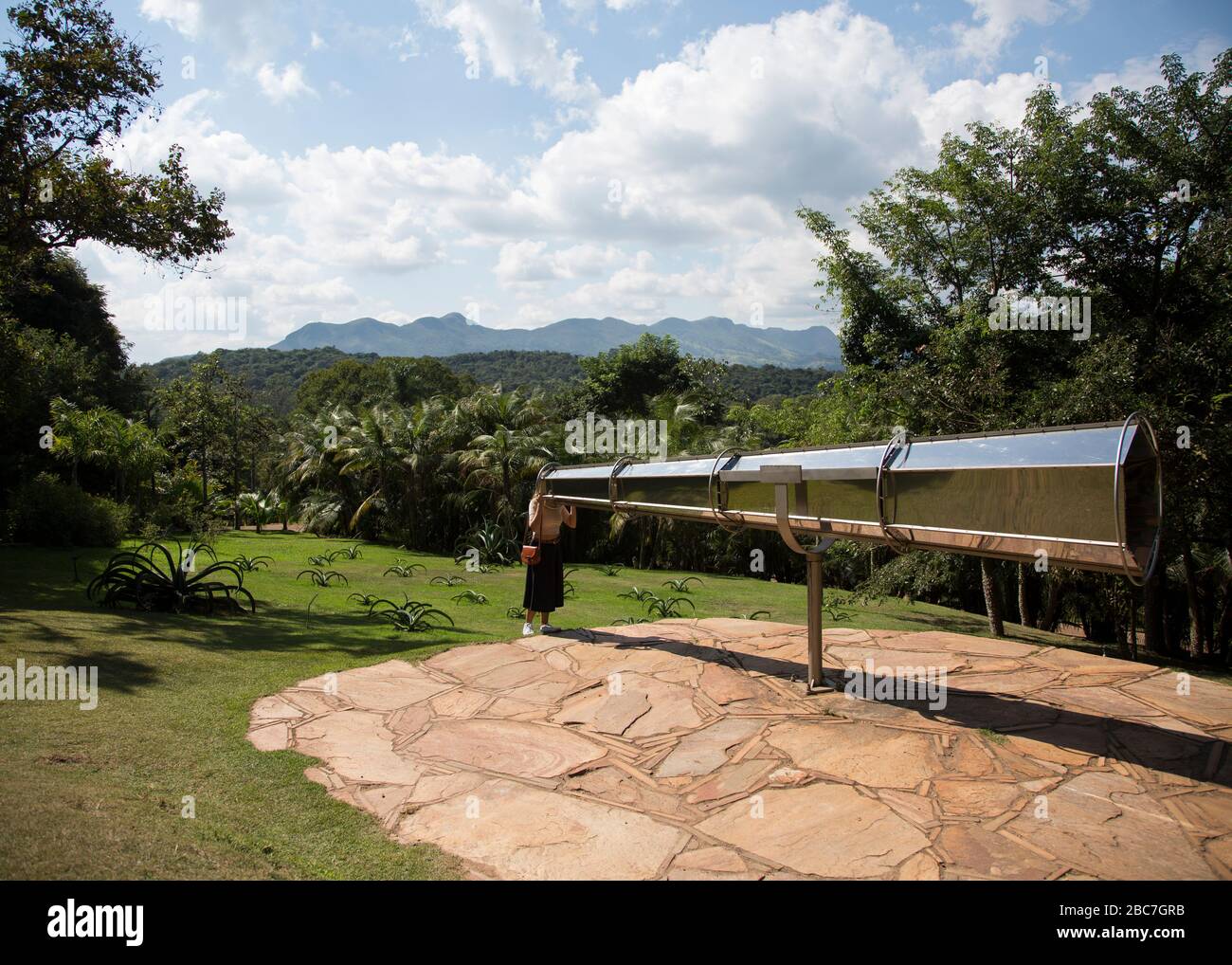 Eine Frau schaut in ein riesiges Teleskop mit Spiegeln im Inneren des Inhotim, dem Institut für zeitgenössische Kunst und Botanischen Gärten in Brasilien. Stockfoto