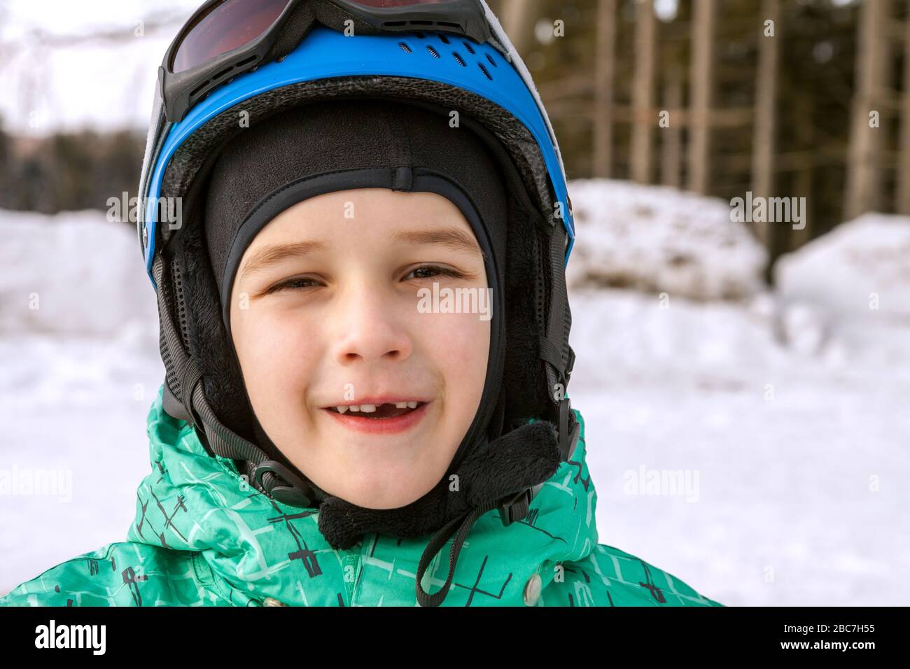 Kleiner Junge auf Bergen im Skihelm mit gefallenem ersten Zahn Stockfoto