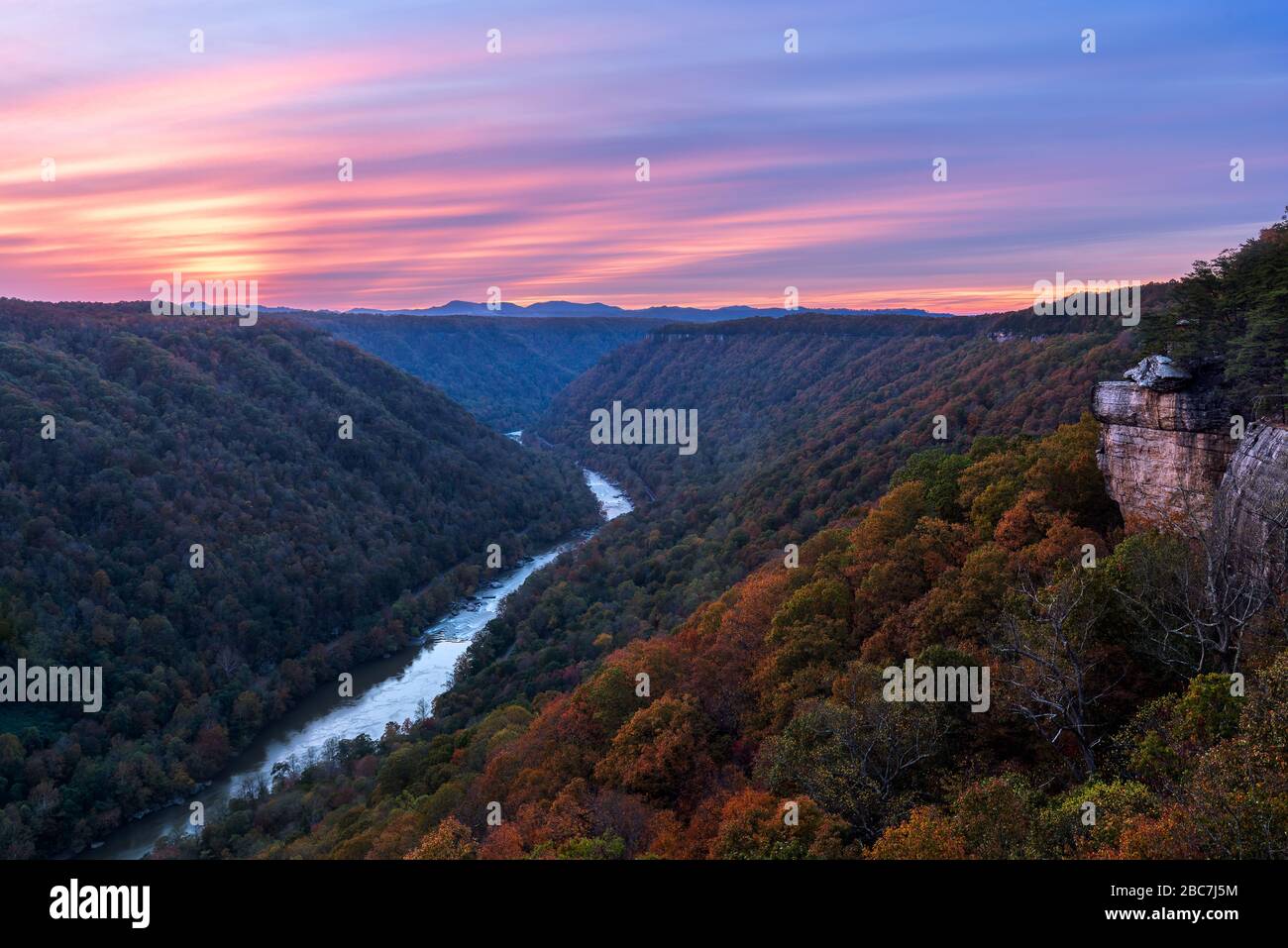 Die tiefe Abendsonne geht über den Beauty Mountain in der New River Gorge von West Virginia und schafft violette Pastelle am Himmel über der Herbstlandschaft a Stockfoto