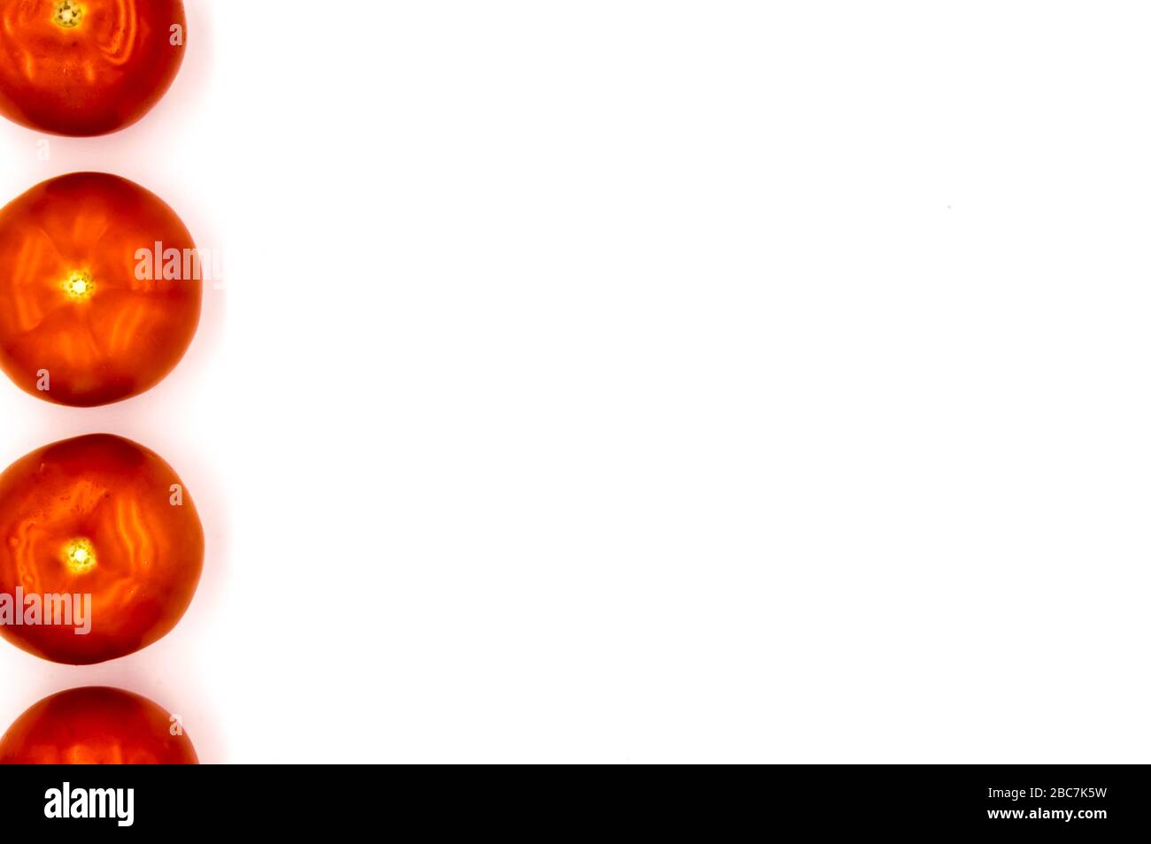 Auf dem linken Rand stehen vier Tomaten auf weißem Hintergrund Stockfoto