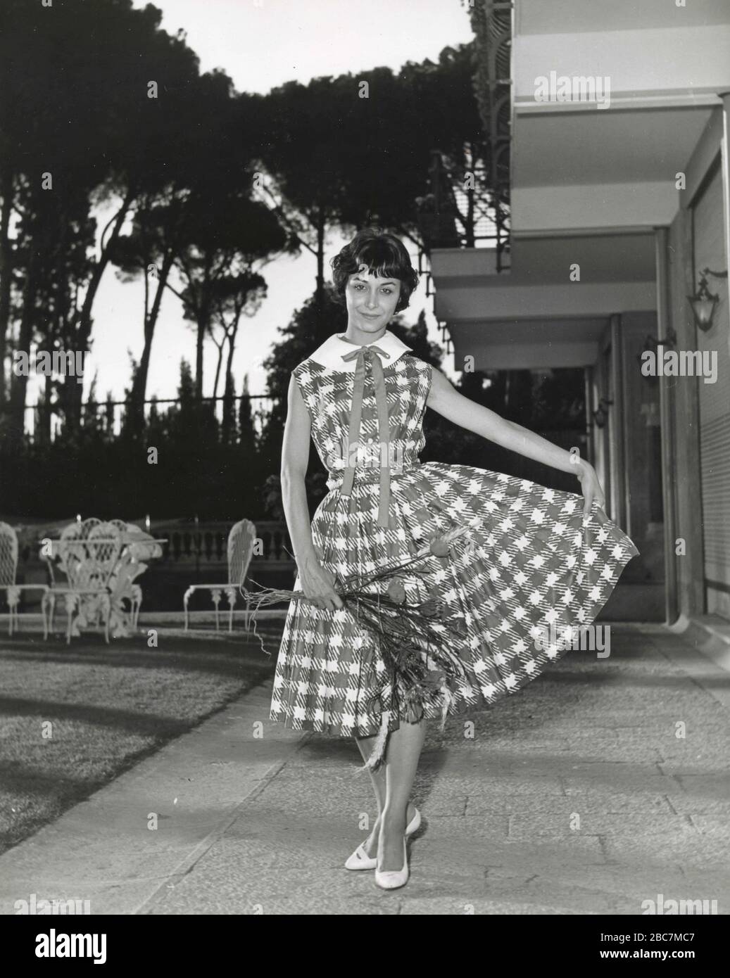 Modell aus den 1960er Jahren, das ein Outfit mit kariertem Kleid und Schleife präsentiert, Italien Stockfoto