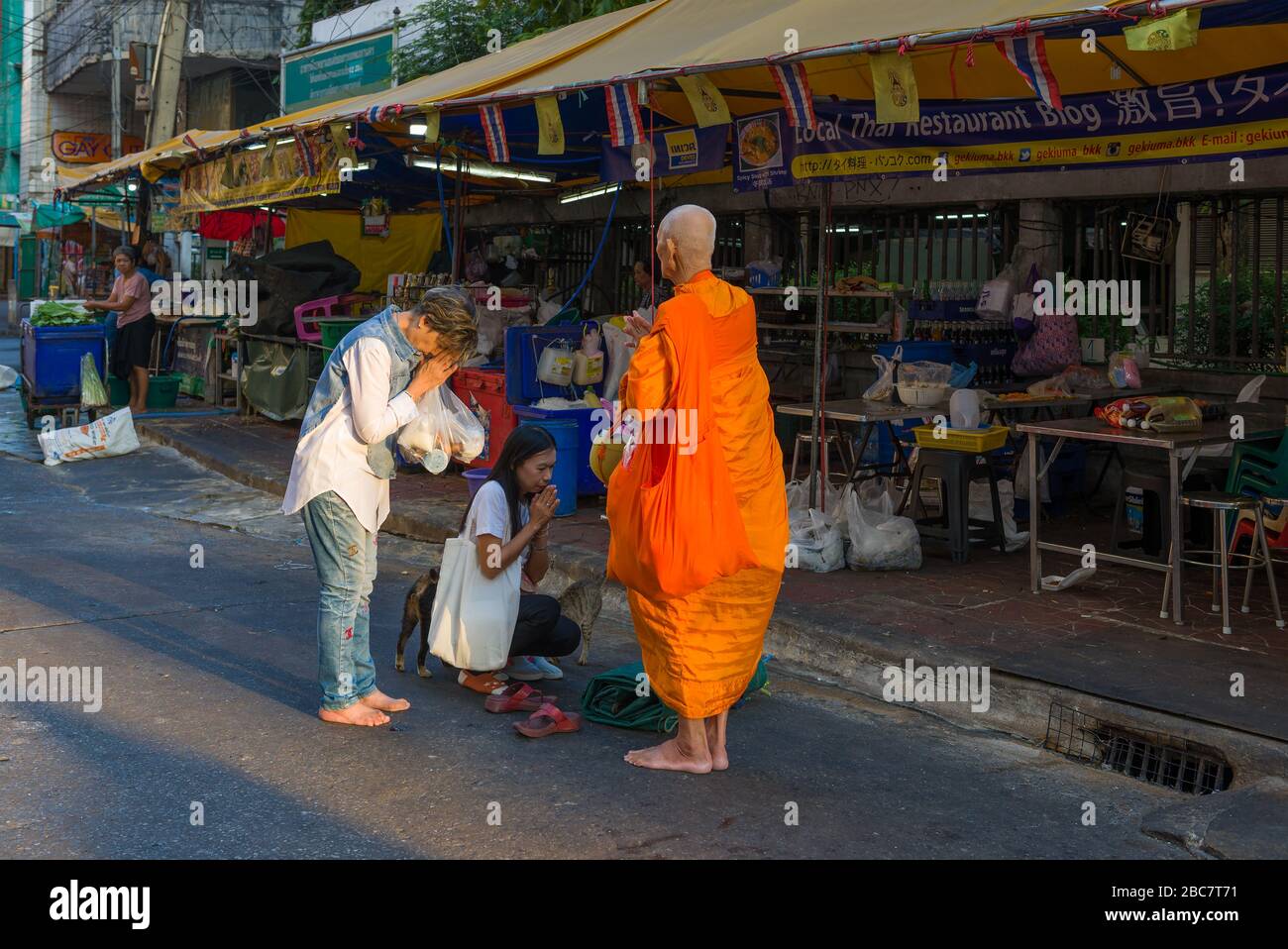 BANGKOK, THAILAND - 31. DEZEMBER 2018: Zwei Frauen erhalten Morgensegen von einem älteren buddhistischen Mönch Stockfoto