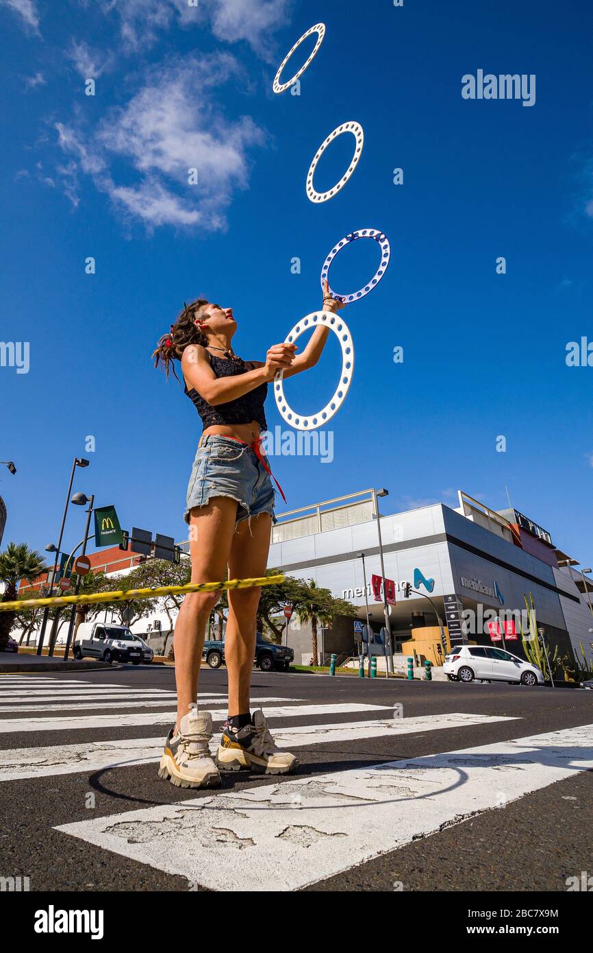 Eine junge Frau jongliert mit 4 Scheiben auf einer Straßenkreuzung Stockfoto