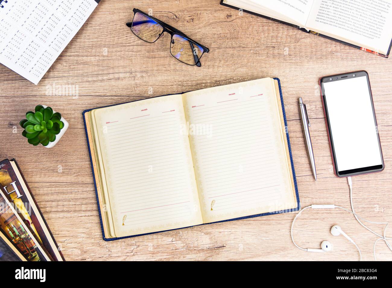 Studienkonzept flacher Laienschreibtisch mit leerem Notizbuch und offener Seite auf Holzhintergrund verspotten Stockfoto