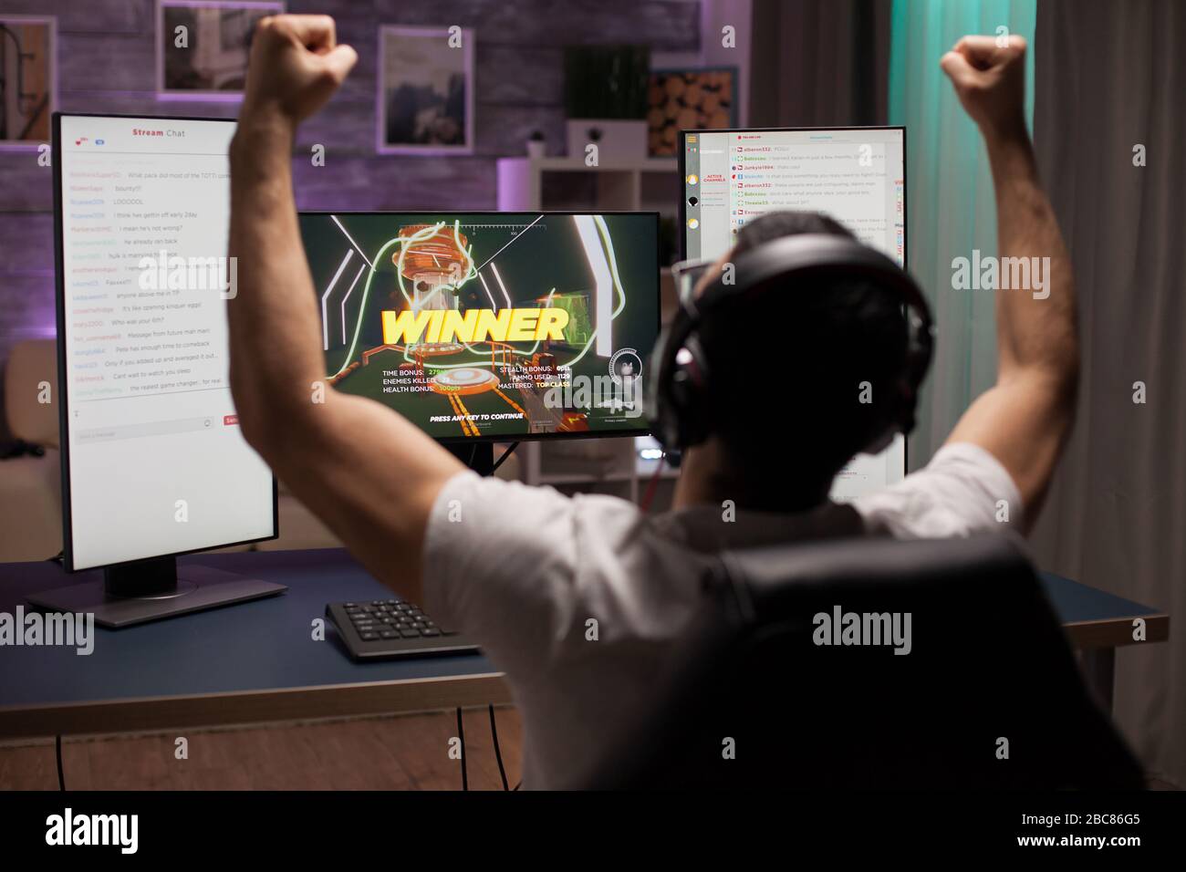Aufgeregter junger Mann mit Händen nach oben, nachdem er einen Wettkampf mit Shooter-Spielen gewonnen hatte. ESport Streaming. Stockfoto