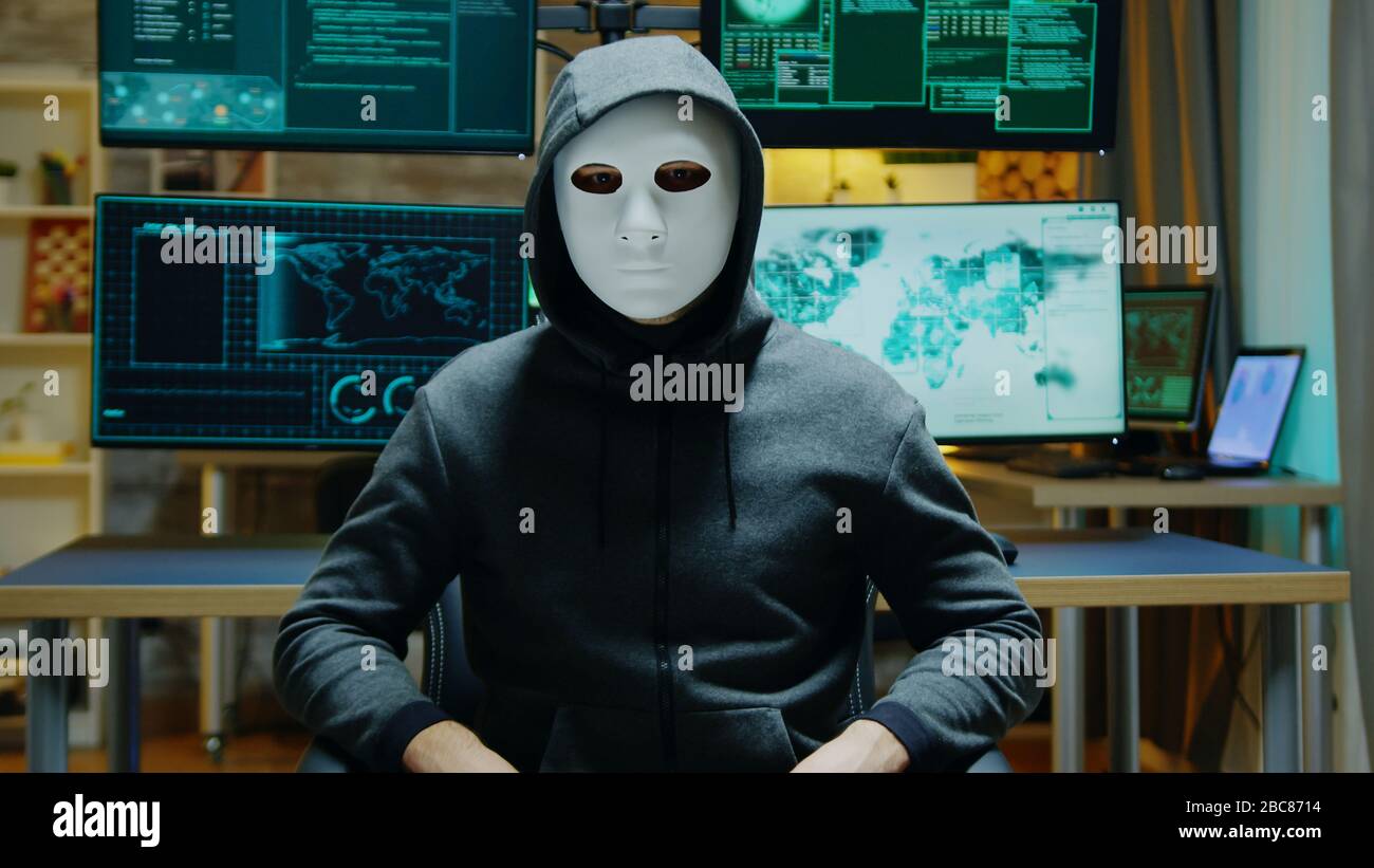 Gefährlicher Hacker, der seine Identität versteckt und dabei eine weiße Maske trägt, während er die erweiterte Realität verwendet, um vertrauliche Daten zu stehlen. Stockfoto