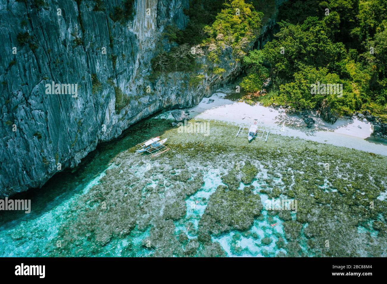 Luftbild der Banca Boote am White Sand Beach und Menschen Schnorcheln über bunte Korallenriffe in El Nido. Philippinen. Stockfoto