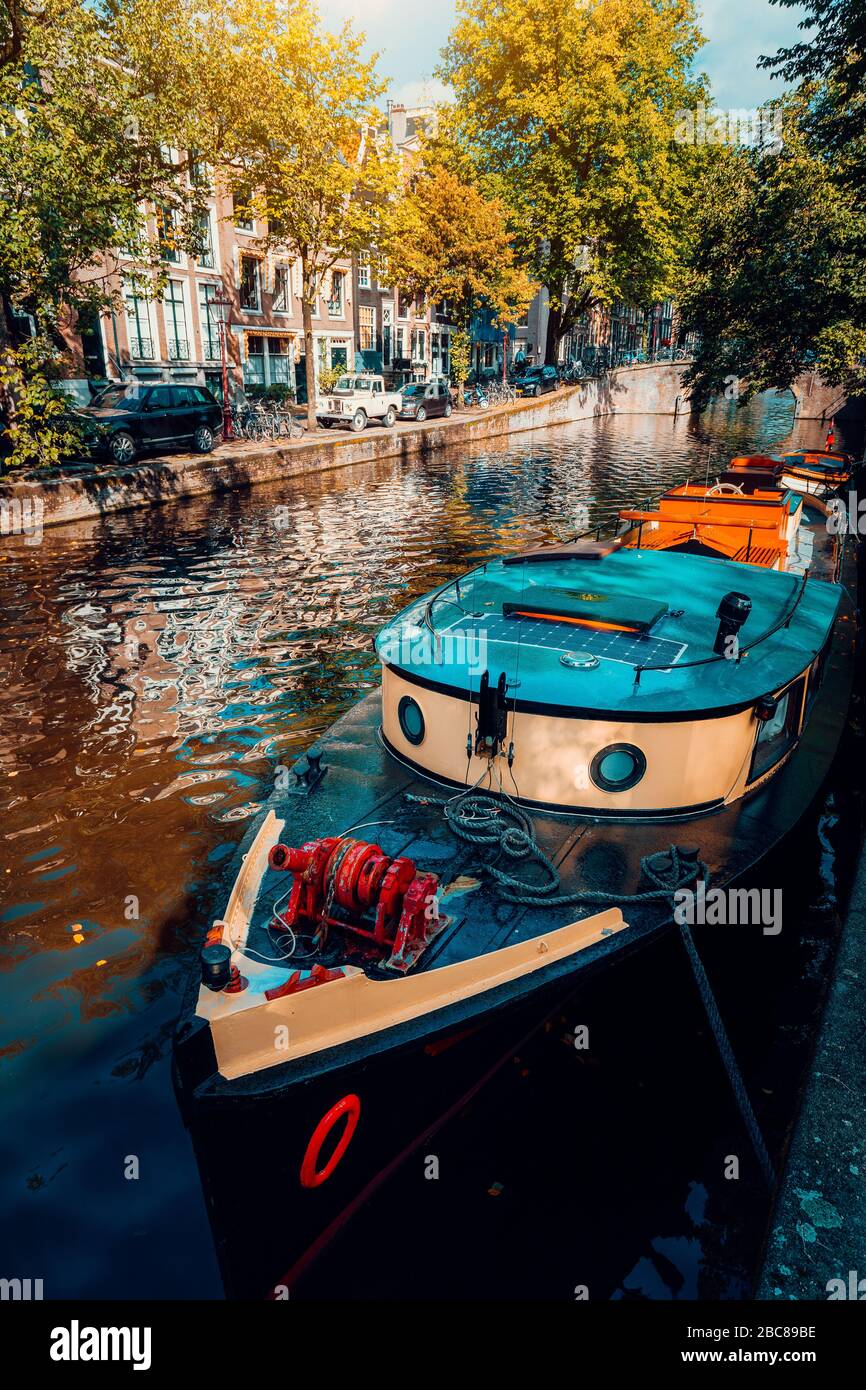 Traditionelles Kreuzfahrt-Boot, das an einem der berühmten Amsterdamer Kanäle an dem schönen, sonnigen Herbsttag festgebunden ist. Stockfoto