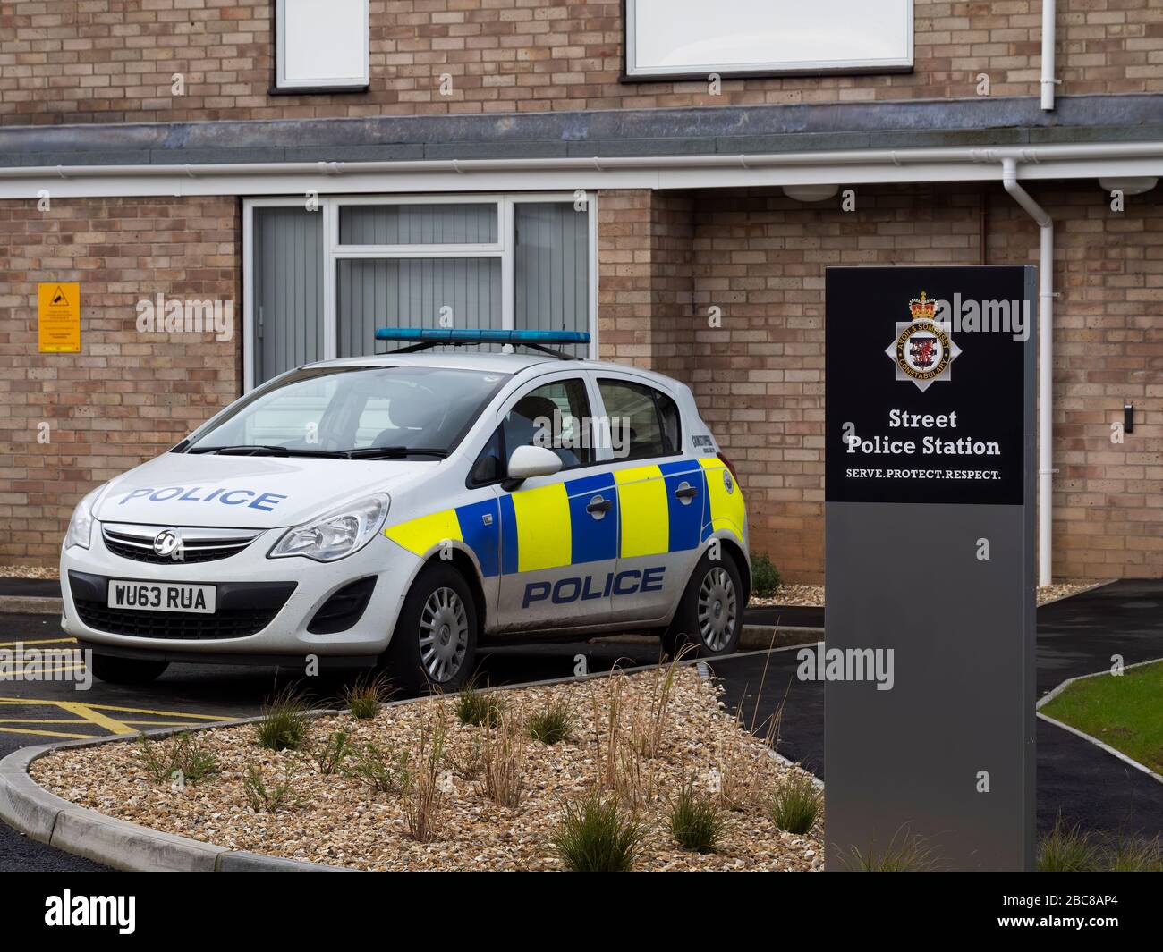 STREET, SOMERSET, ENGLAND - 9. MÄRZ 2020: Polizeiwagen vor einer Polizeistation geparkt. Sichtbares Logo Leitbild: Dienen. Schützen. Respekt. Nein Stockfoto