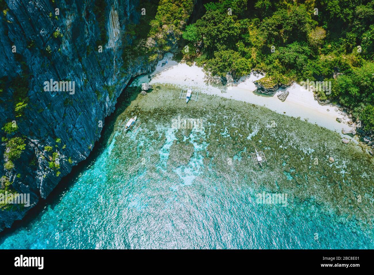 Antenne drone Ansicht von unbewohnten tropischen Insel mit robusten Kalkstein Berge, Regenwald Dschungel, Sandstrand mit Korallenriff und touristische banca Bo Stockfoto