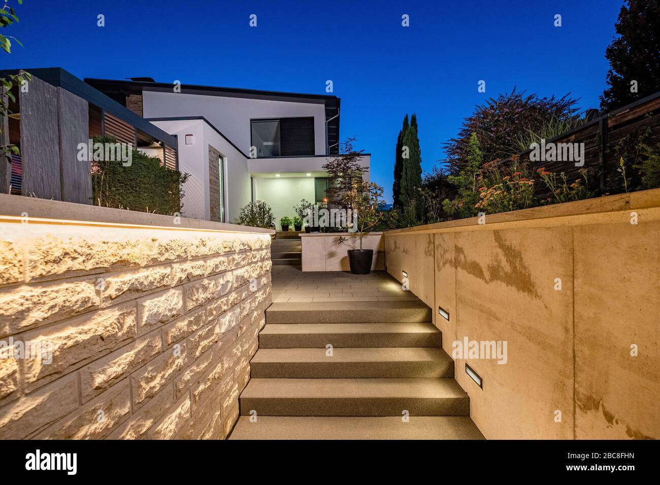 Hauseingang mit Zufahrtsweg und Treppe in der Nacht mit stimmungsvollem Lichtkonzept Stockfoto