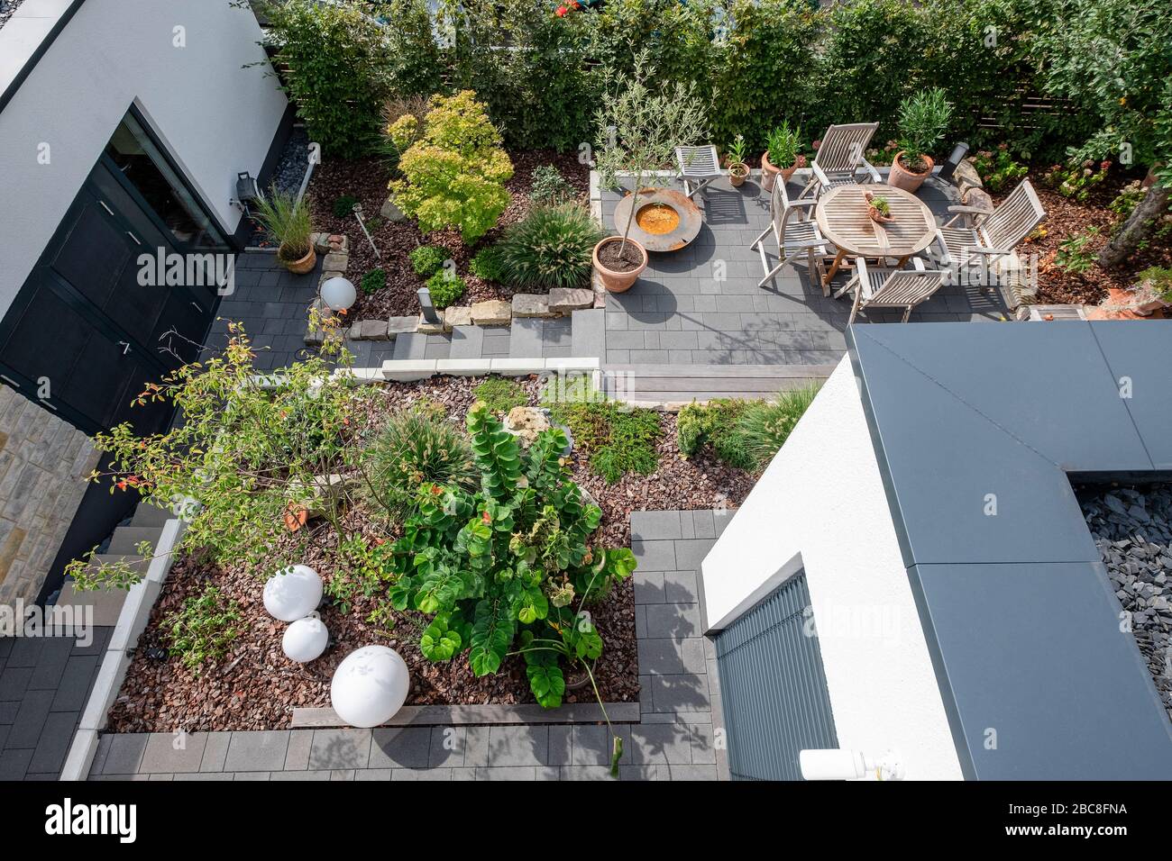 Überblick über eine gepflegte Gartenlandschaft mit Terrasse, Pflanzenbeeten und Zufahrtswegen Stockfoto