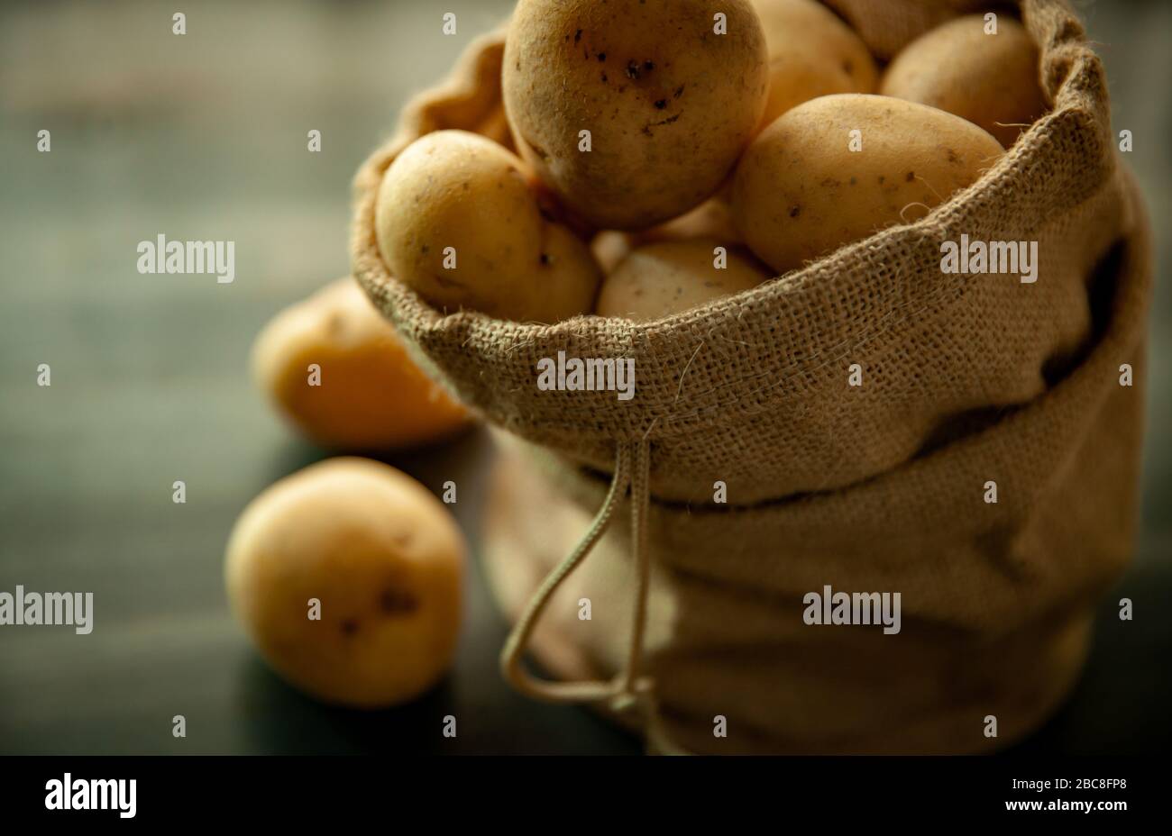 Kartoffeln in einem Sacktuch auf rustikalem Holzhintergrund auf weichen Fenstern, leichte Speisen im Vintage-Stil Stockfoto