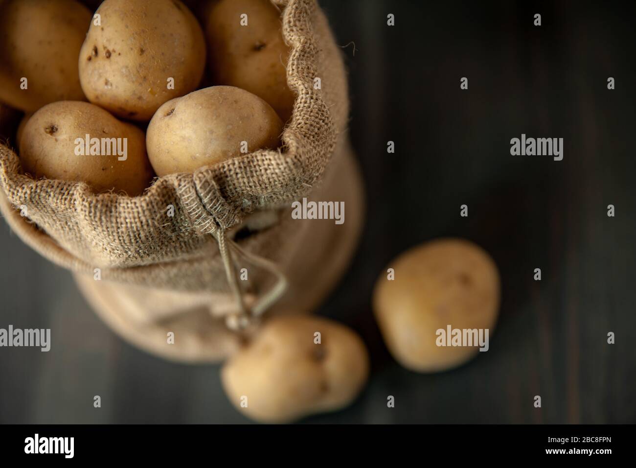 Kartoffeln in einem Sacktuch auf rustikalem Holzhintergrund auf weichen Fenstern, leichte Speisen im Vintage-Stil Stockfoto